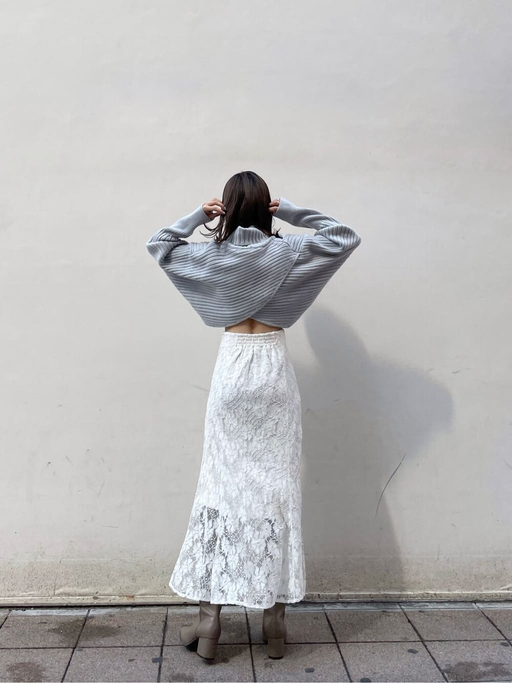 ホワイト系のスカート、ベージュ系のブーツ、ブルー系のニット/セーターを着用したレディースの秋コーディネートの2枚目の写真