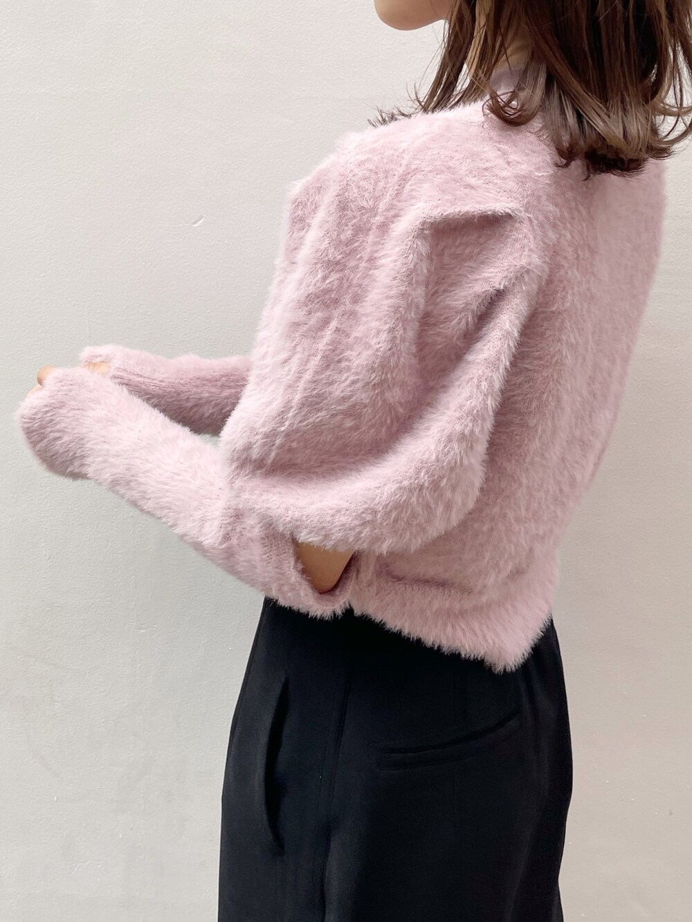 ピンク系のニット/セーター、ブラック系のスカート、ブラック系のブーツを着用したレディースの冬コーディネートの5枚目の写真