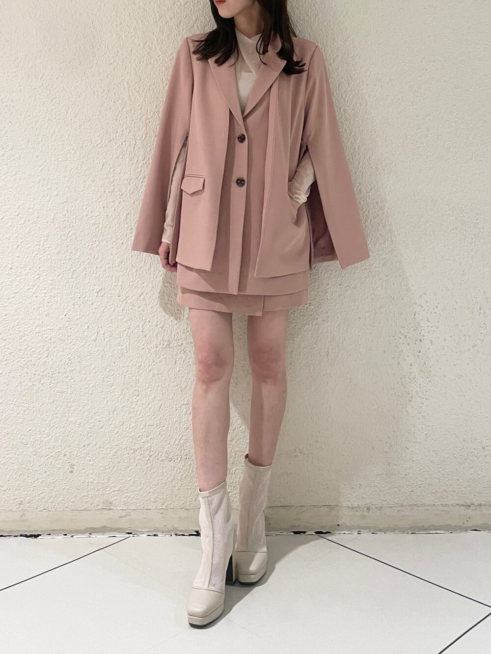 ピンク系のテーラードジャケット、ピンク系のスカート、ホワイト系のブーツを着用したレディースの冬コーディネートの3枚目の写真