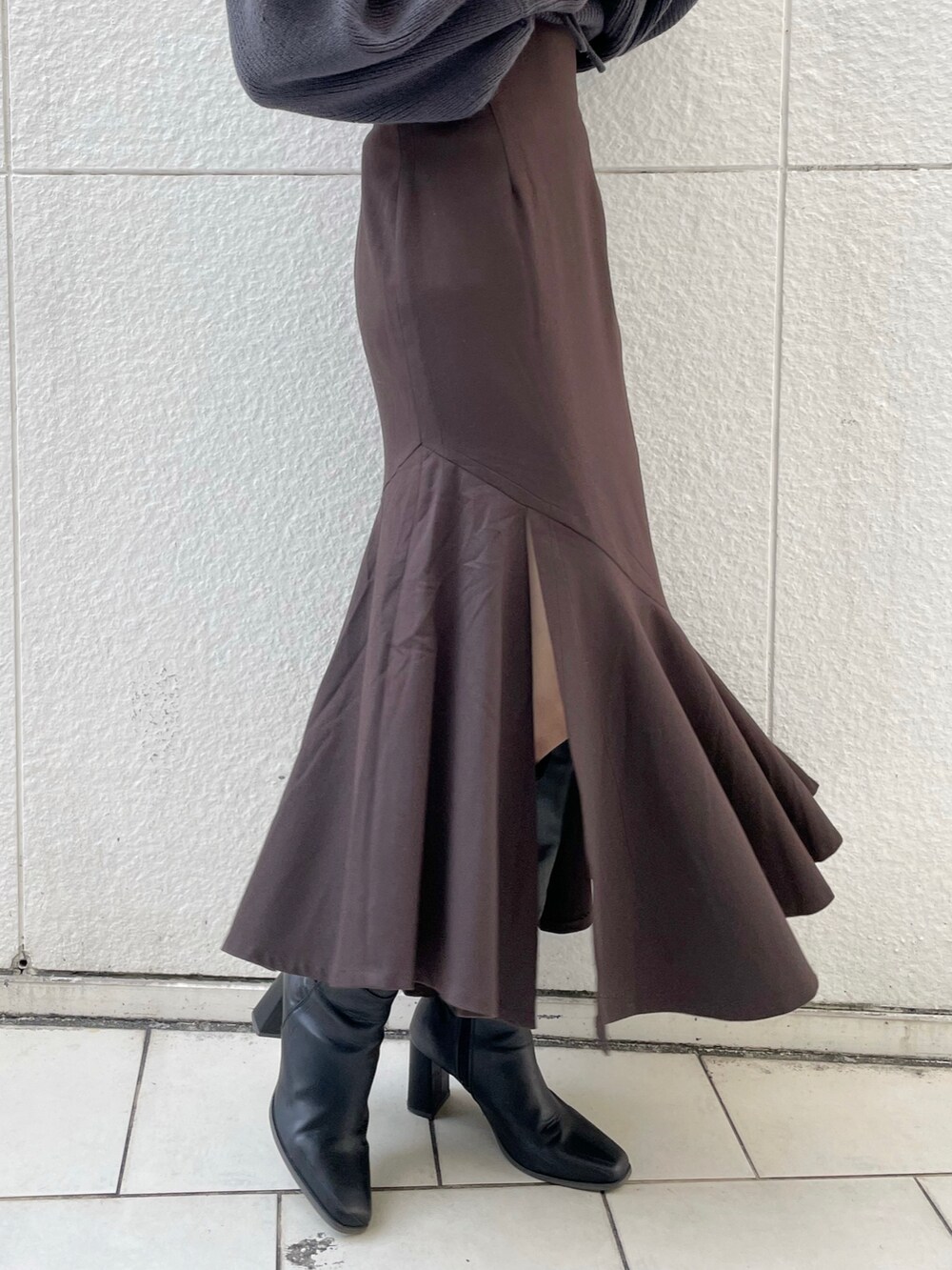 グレー系のニット/セーター、ブラウン系のスカート、ブラック系のブーツを着用したレディースの冬コーディネートの7枚目の写真