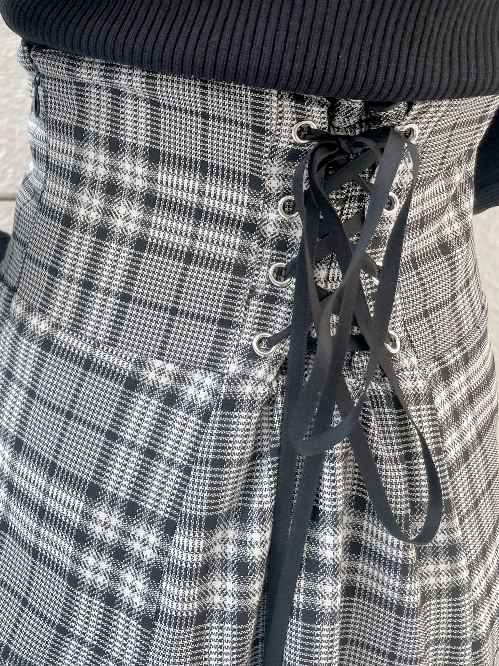 ブラック系のニット/セーター、グレー系のスカート、ブラック系のブーツを着用したレディースの秋コーディネートの7枚目の写真