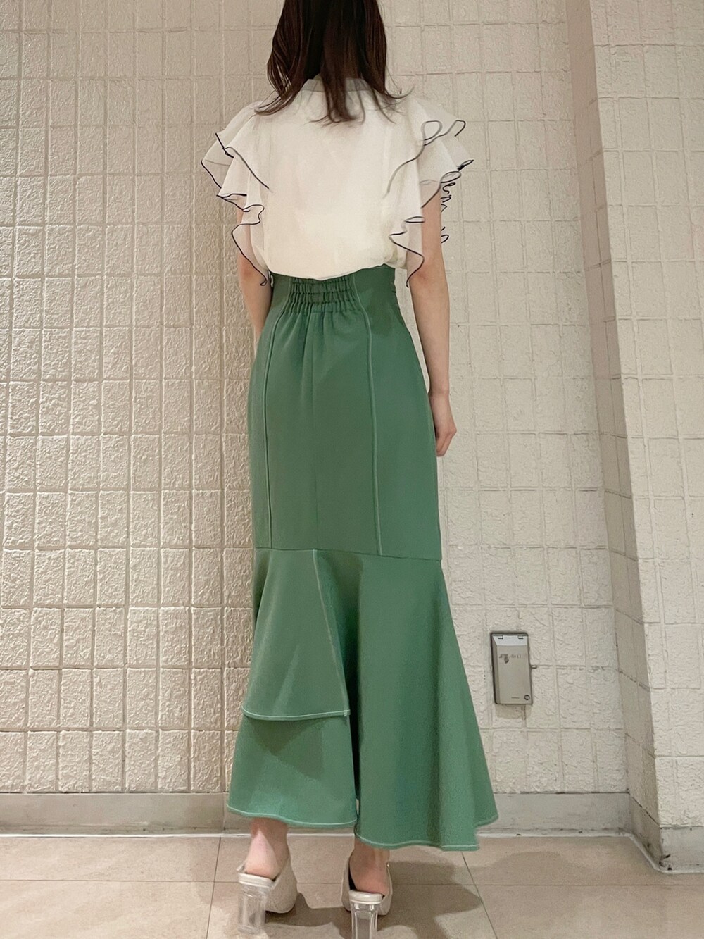 ホワイト系のシャツ/ブラウス、グリーン系のスカート、ホワイト系のパンプスを着用したレディースの春コーディネートの3枚目の写真