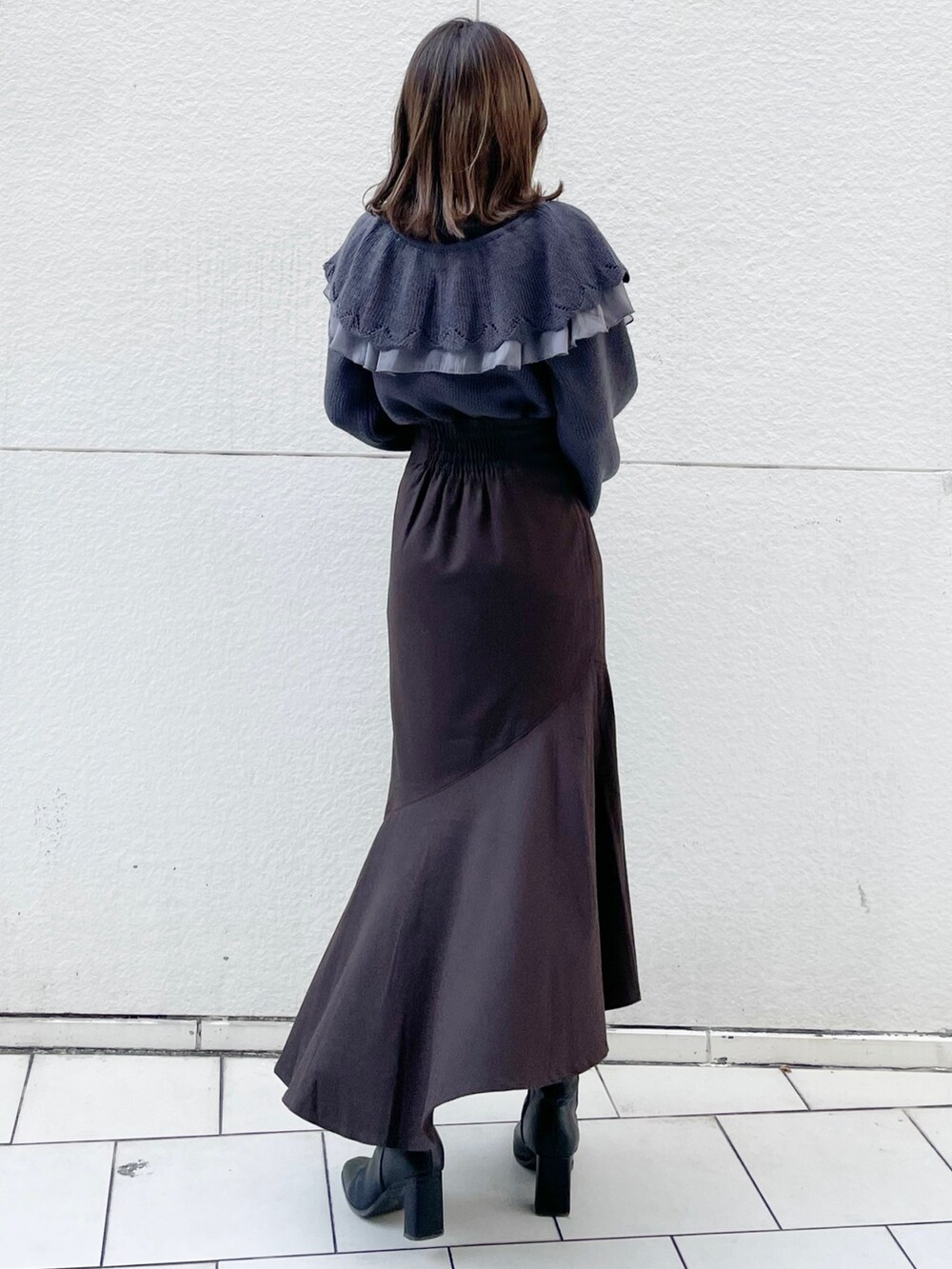 グレー系のニット/セーター、ブラウン系のスカート、ブラック系のブーツを着用したレディースの冬コーディネートの3枚目の写真