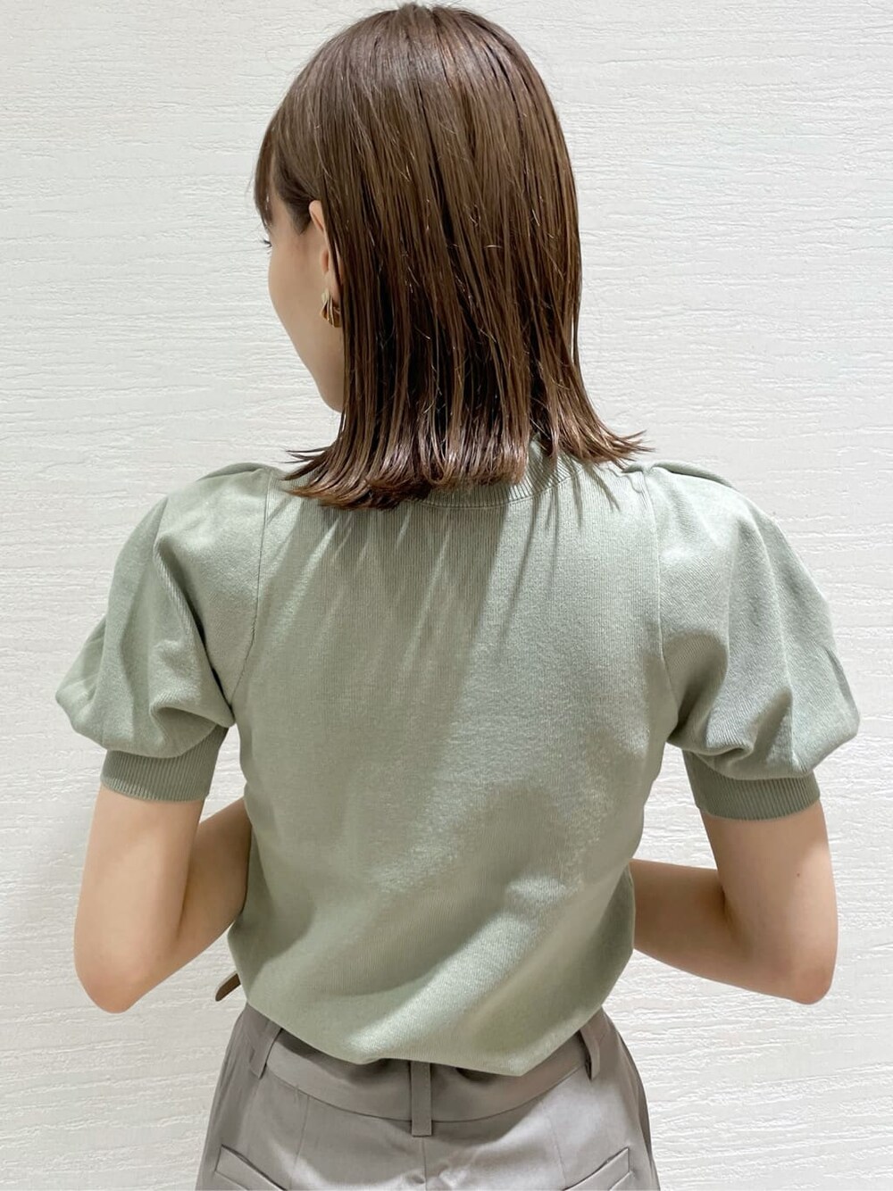 グレー系のその他パンツ、ホワイト系のハンドバッグ、グリーン系のニット/セーターを着用したレディースの夏コーディネートの6枚目の写真