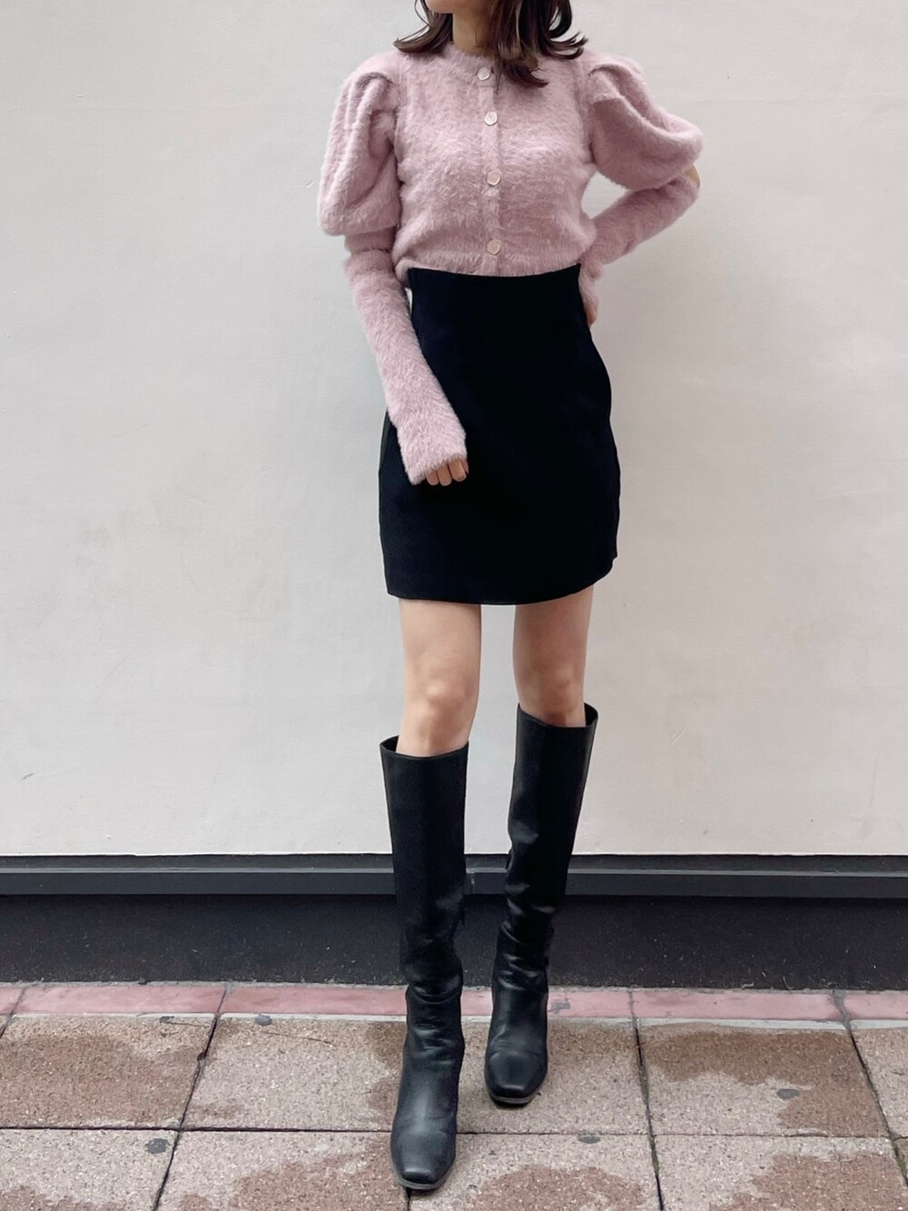 ピンク系のニット/セーター、ブラック系のスカート、ブラック系のブーツを着用したレディースの冬コーディネートの3枚目の写真