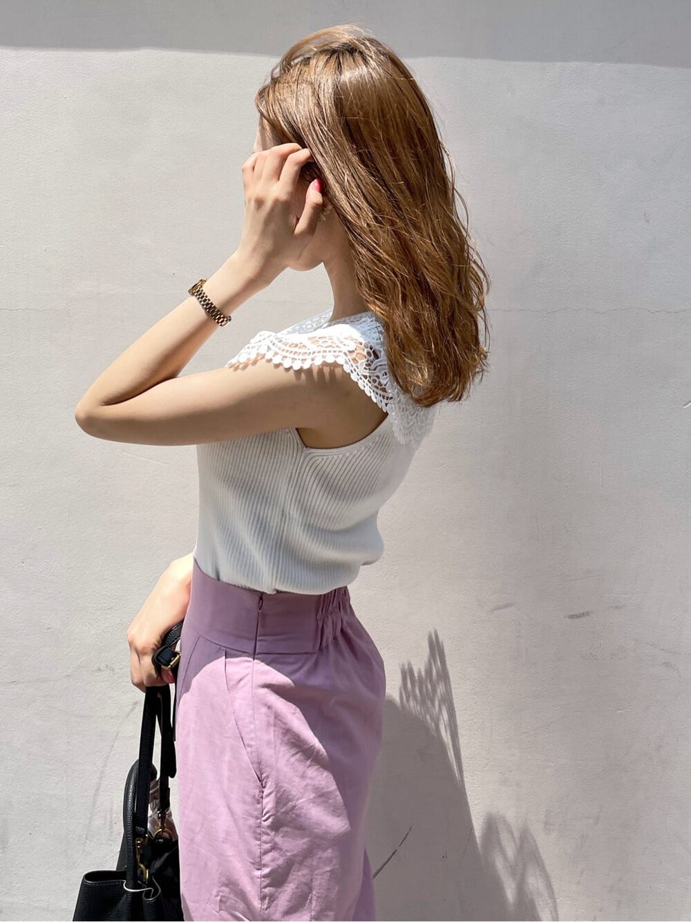 ブラック系のハンドバッグ、ピンク系のスカート、パープル系のサンダルを着用したレディースの夏コーディネートの6枚目の写真