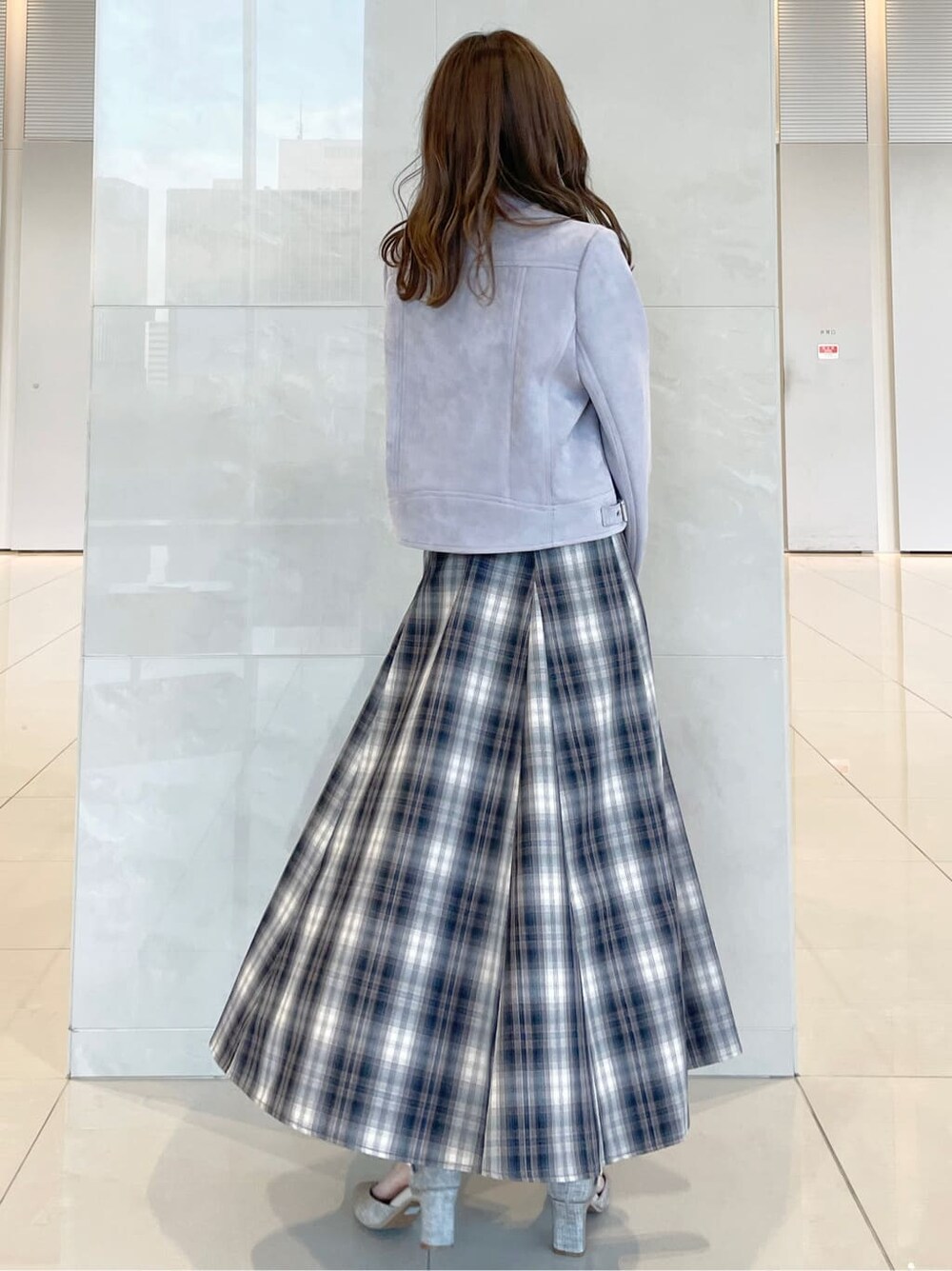 ベージュ系のワンピース、パープル系のライダースジャケット、グレー系のパンプスを着用したレディースの秋コーディネートの3枚目の写真