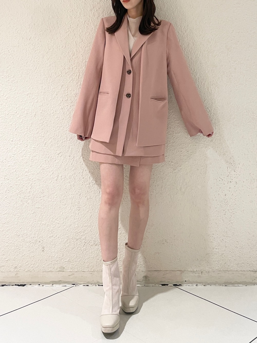 ピンク系のテーラードジャケット、ピンク系のスカート、ホワイト系のブーツを着用したレディースの冬コーディネートの6枚目の写真