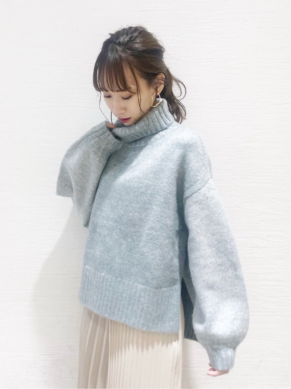 ベージュ系のスカート、ホワイト系のブーツ、グレー系のニット/セーターを着用したレディースの秋コーディネートの2枚目の写真