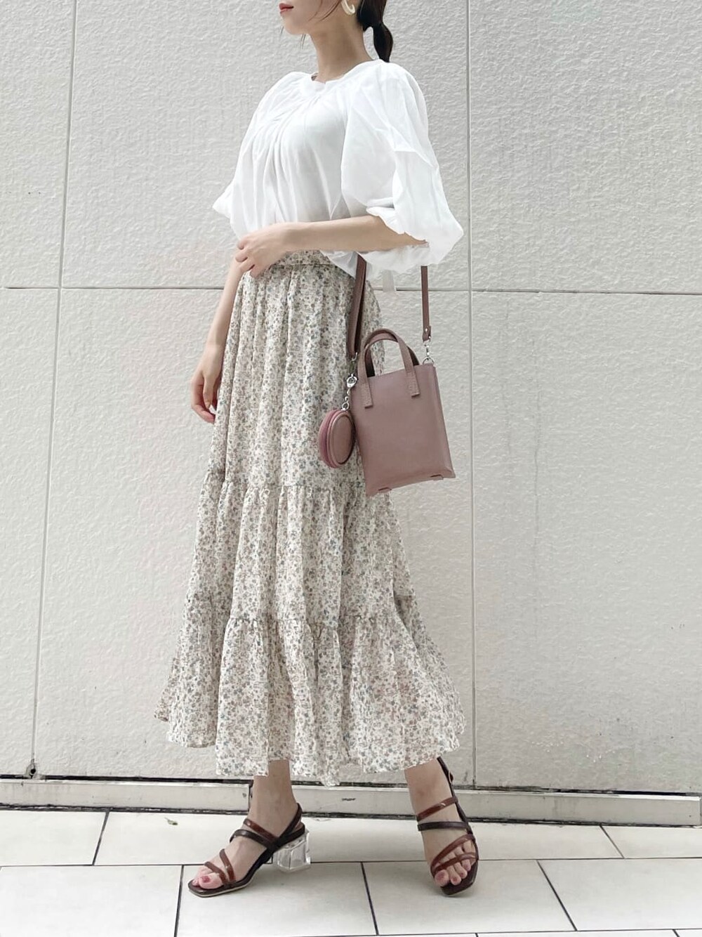 ブラウン系のハンドバッグ、ブラウン系のサンダル、ホワイト系のシャツ/ブラウスを着用したレディースの夏コーディネートの2枚目の写真