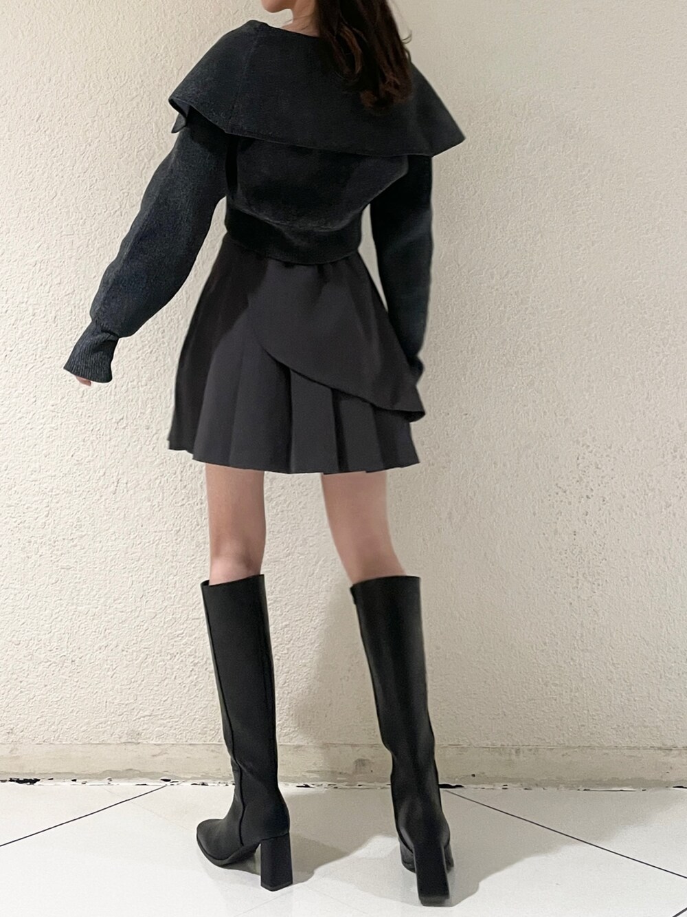 グレー系のニット/セーター、グレー系のスカート、ブラック系のブーツを着用したレディースの秋コーディネートの4枚目の写真