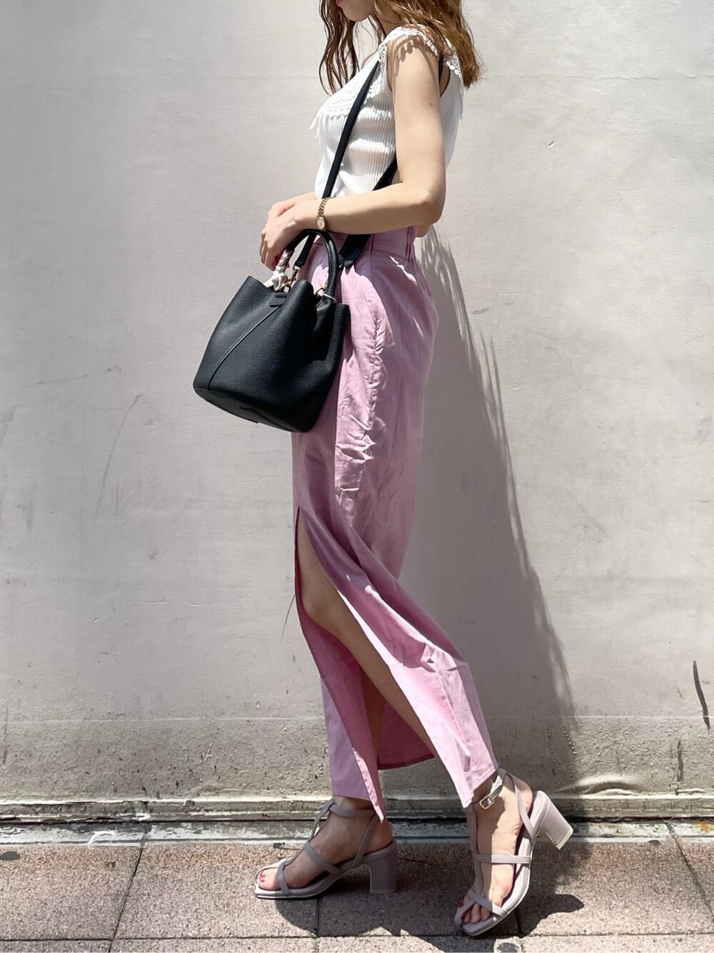 ブラック系のハンドバッグ、ピンク系のスカート、パープル系のサンダルを着用したレディースの夏コーディネートの3枚目の写真