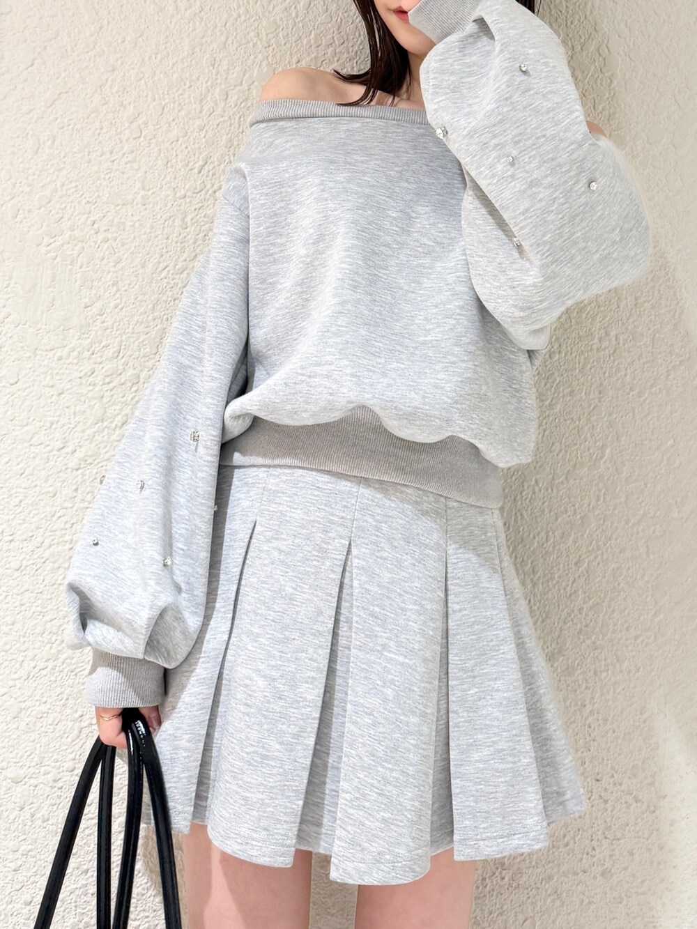 グレー系のスウェット、グレー系のスカート、ブラック系のハンドバッグを着用したレディースの春コーディネートの5枚目の写真