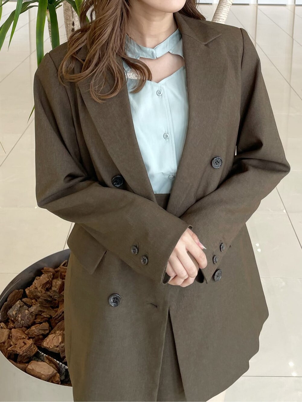 グリーン系のシャツ/ブラウス、ブラウン系のテーラードジャケット、ブラウン系のスカートを着用したレディースの秋コーディネートの4枚目の写真