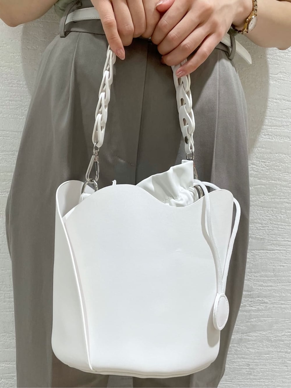 グレー系のその他パンツ、ホワイト系のハンドバッグ、グリーン系のニット/セーターを着用したレディースの夏コーディネートの10枚目の写真