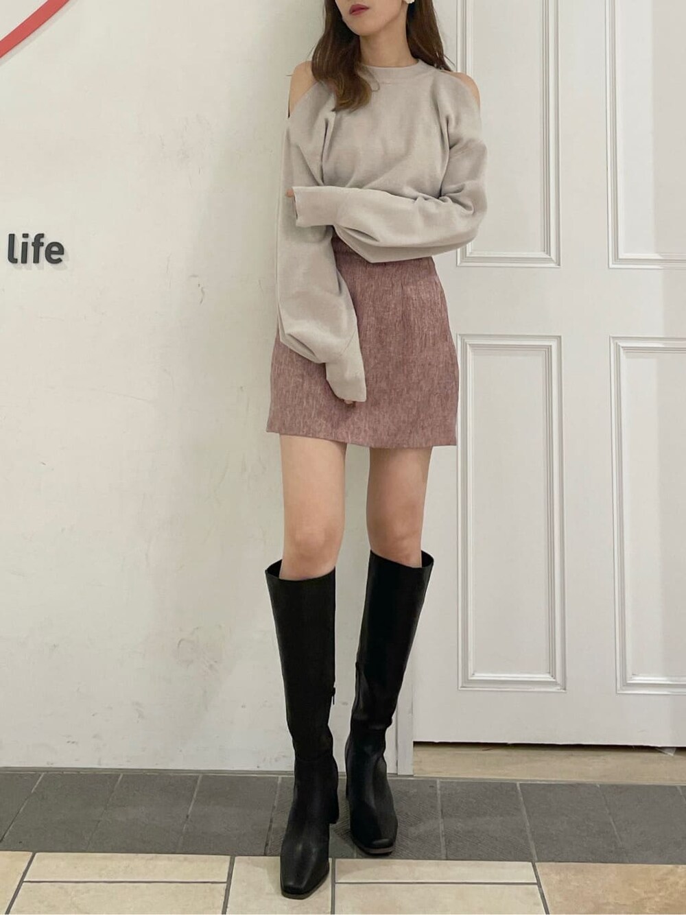 グレー系のニット/セーター、レッド系のスカート、ブラック系のブーツを着用したレディースの夏コーディネートの3枚目の写真