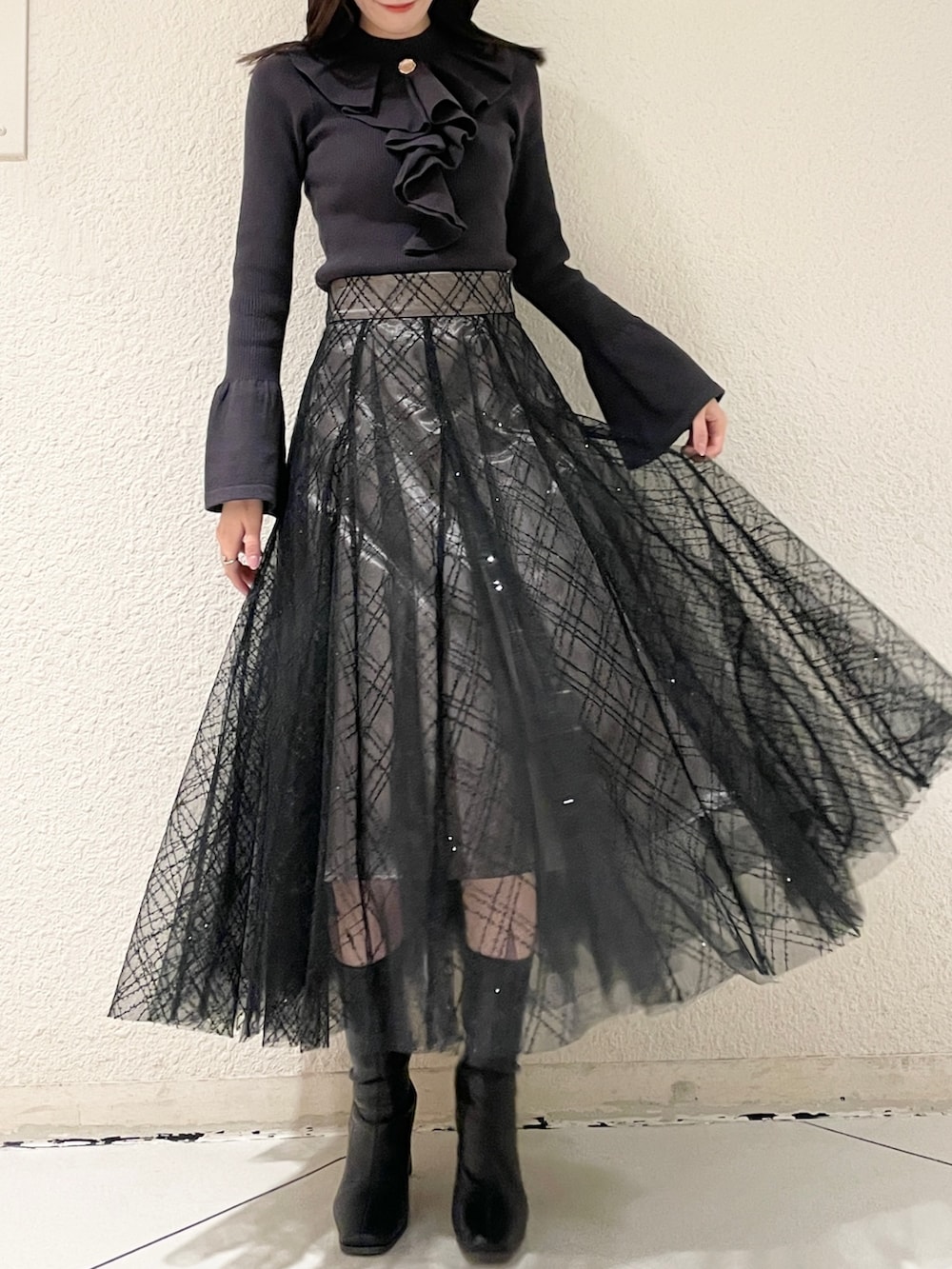 ブラック系のブーツ、ブラック系のニット/セーター、ブラック系のスカートを着用したレディースの冬コーディネートの2枚目の写真