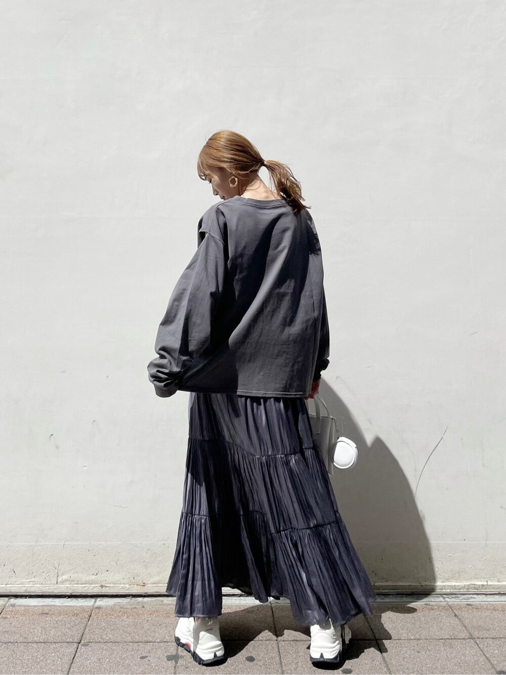 パープル系のスカート、ホワイト系のスニーカー、ホワイト系のハンドバッグを着用したレディースの春コーディネートの3枚目の写真