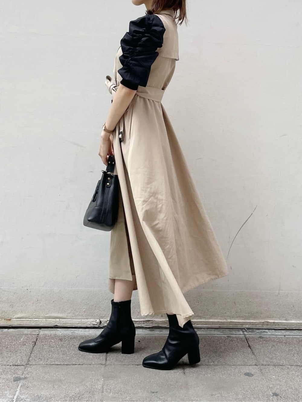 ベージュ系のワンピース、ブラック系のハンドバッグ、ブラック系のニット/セーターを着用したレディースの秋コーディネートの2枚目の写真