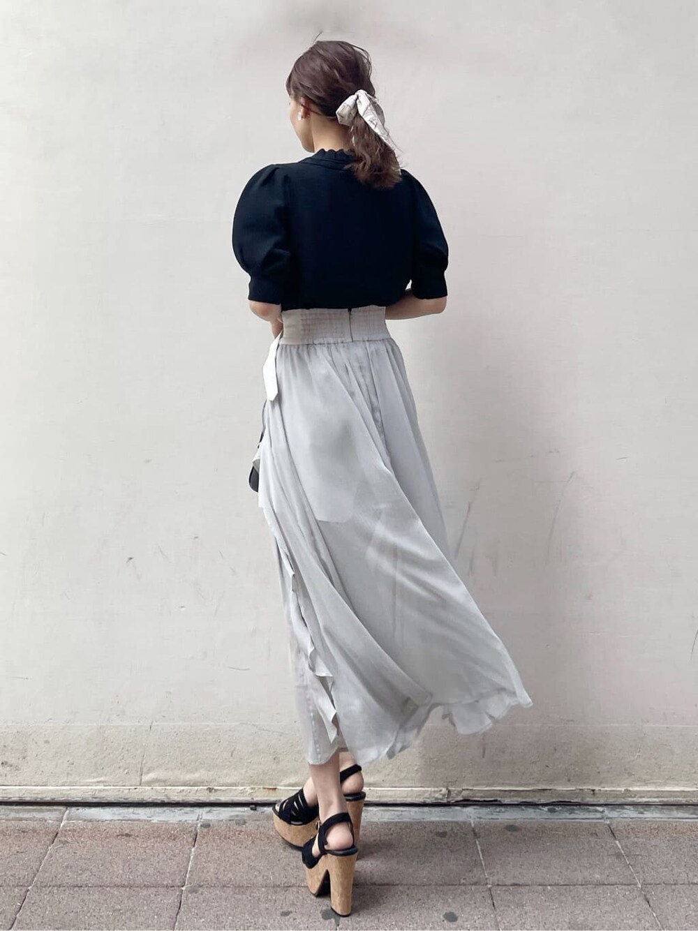 グレー系のスカート、ブラック系のサンダル、ホワイト系のニット/セーターを着用したレディースの春コーディネートの3枚目の写真