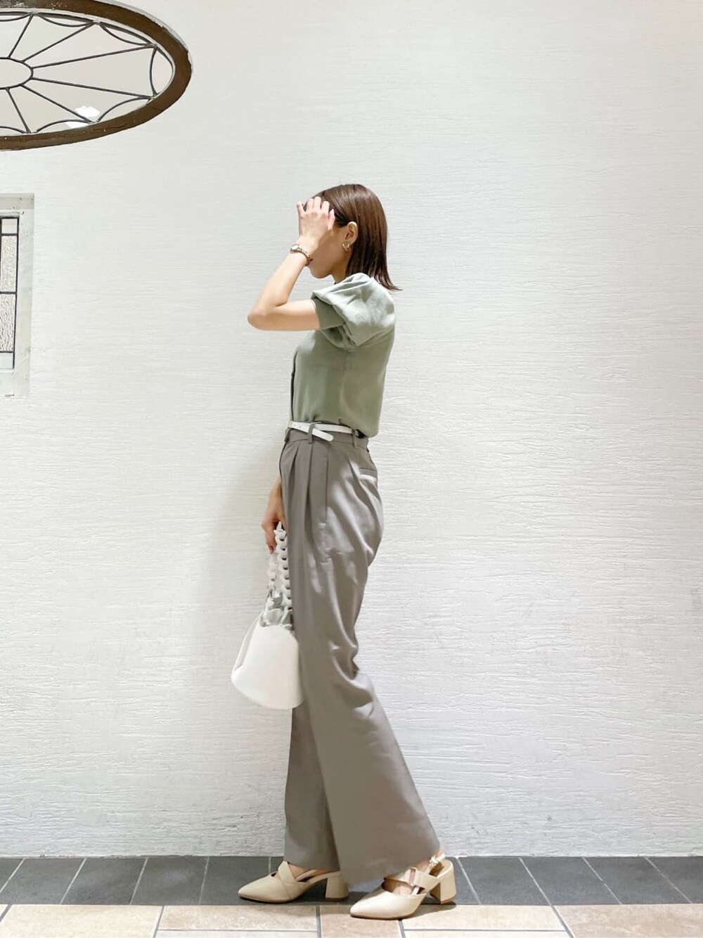 グレー系のその他パンツ、ホワイト系のハンドバッグ、グリーン系のニット/セーターを着用したレディースの夏コーディネートの2枚目の写真
