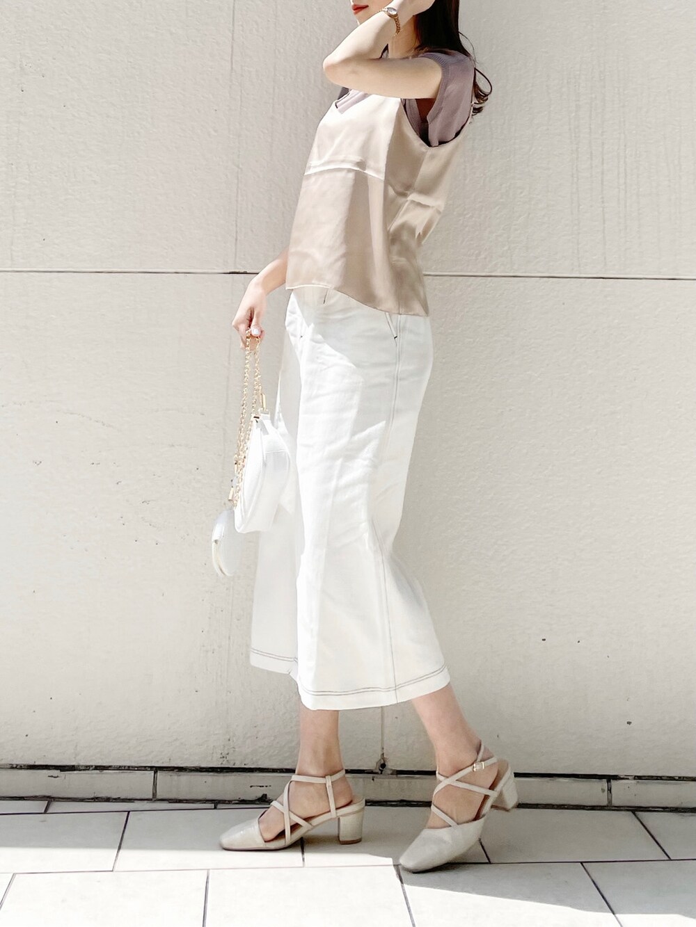 ホワイト系のスカート、ホワイト系のパンプス、ホワイト系のショルダーバッグを着用したレディースの春コーディネートの2枚目の写真