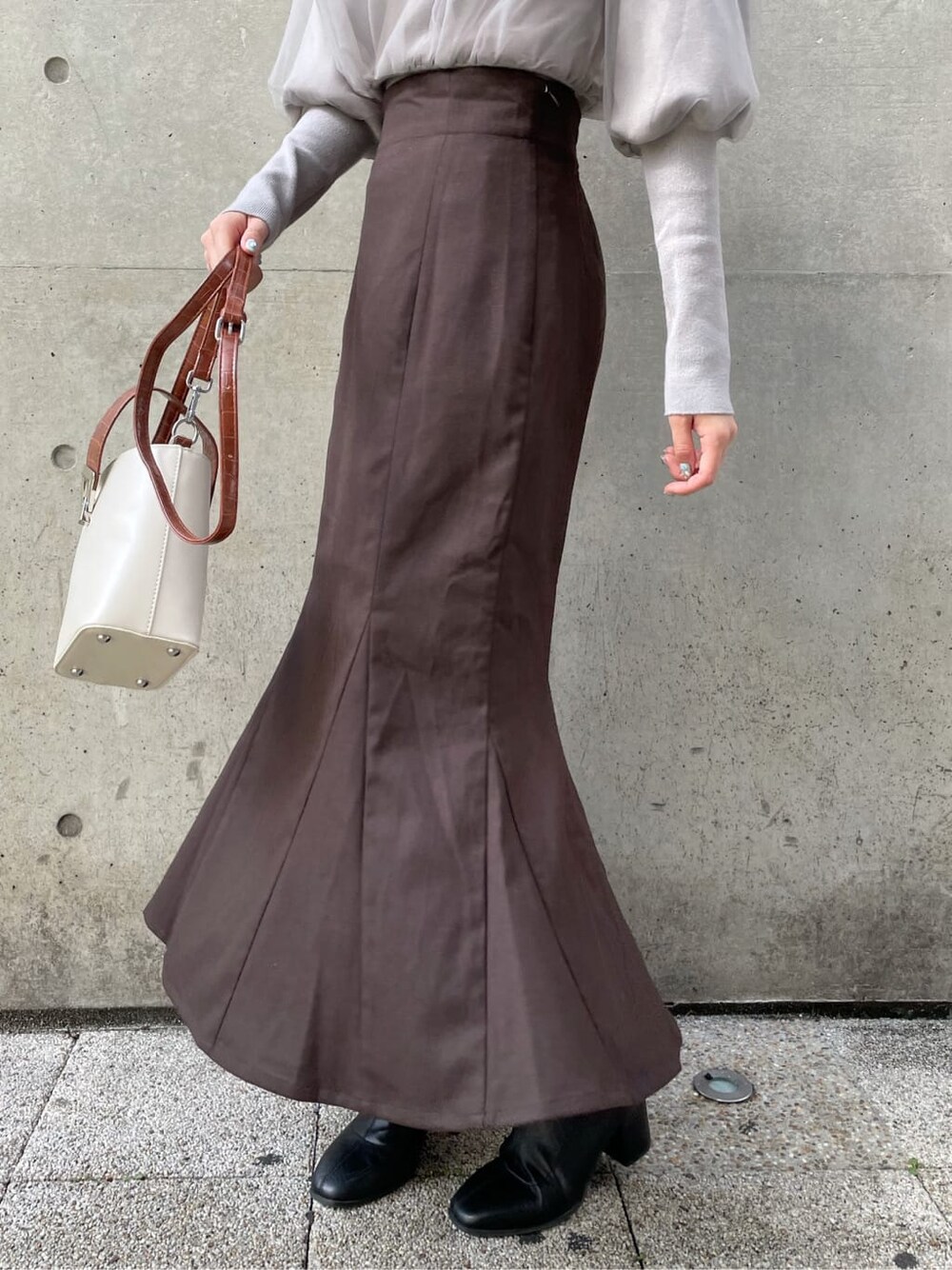 グレー系のニット/セーター、ブラック系のブーツ、ブラウン系のスカートを着用したレディースの秋コーディネートの9枚目の写真