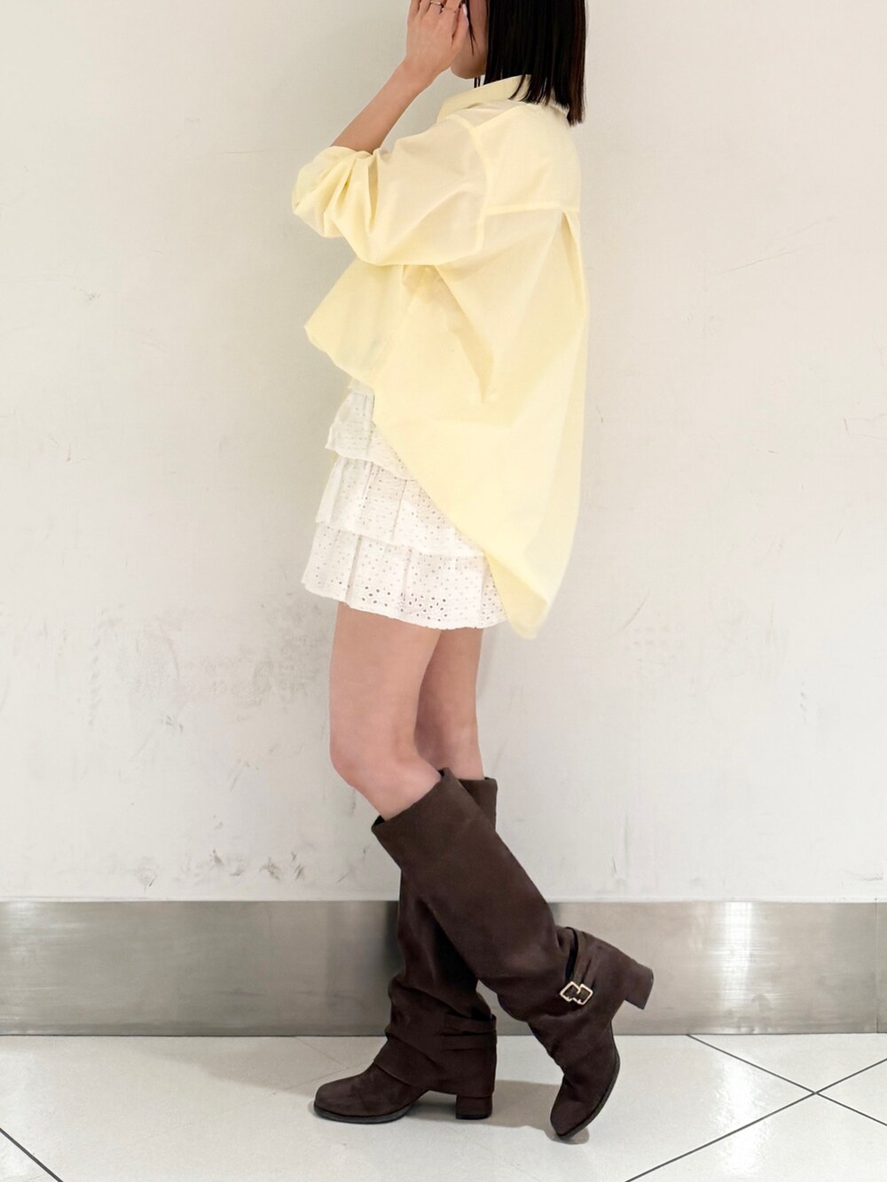 イエロー系のシャツ/ブラウス、ホワイト系のスカート、ブラウン系のブーツを着用したレディースの春コーディネートの2枚目の写真