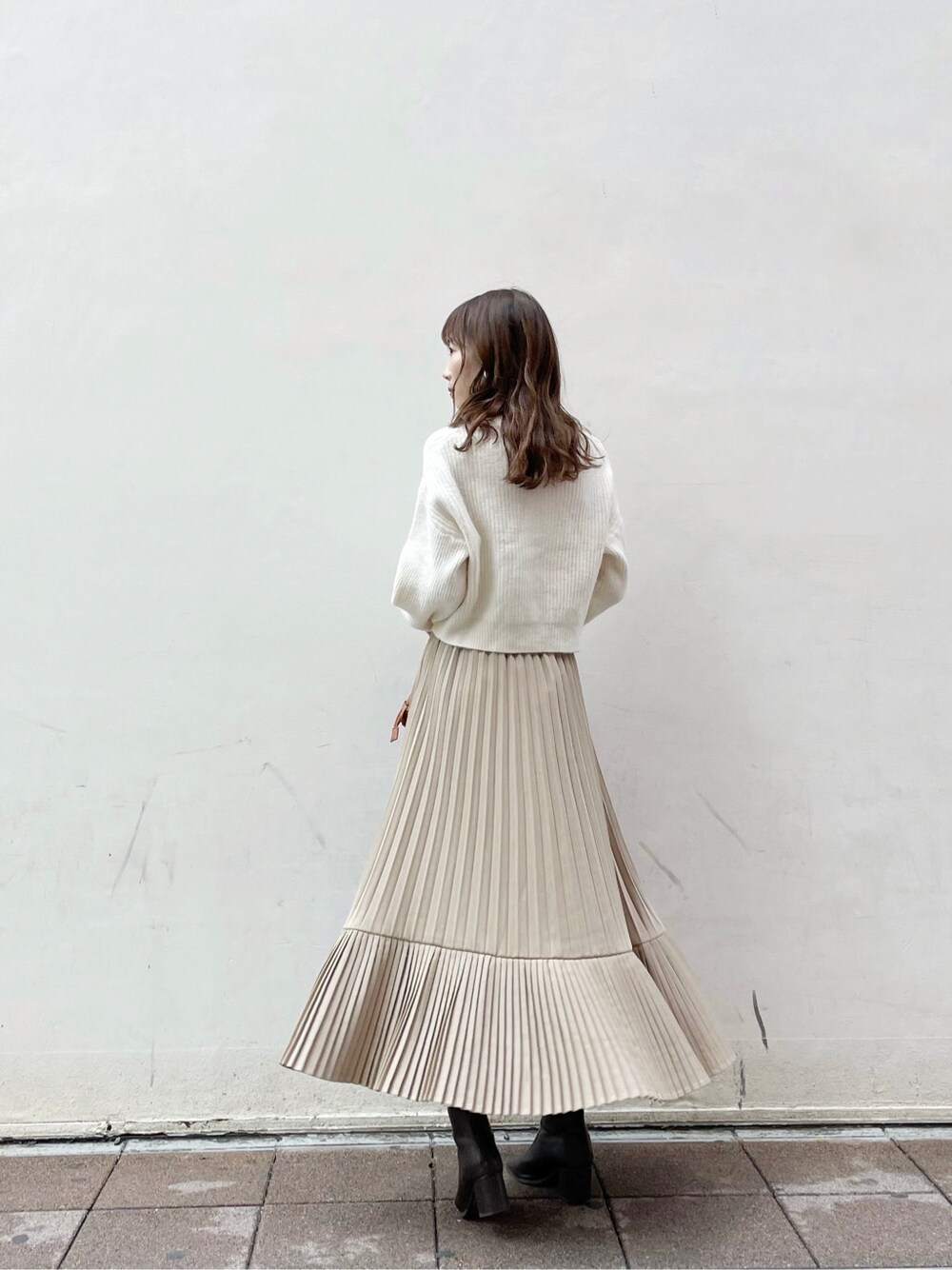 ブラウン系のクラッチバッグ、ホワイト系のニット/セーター、ブラウン系のブーツを着用したレディースの冬コーディネートの3枚目の写真