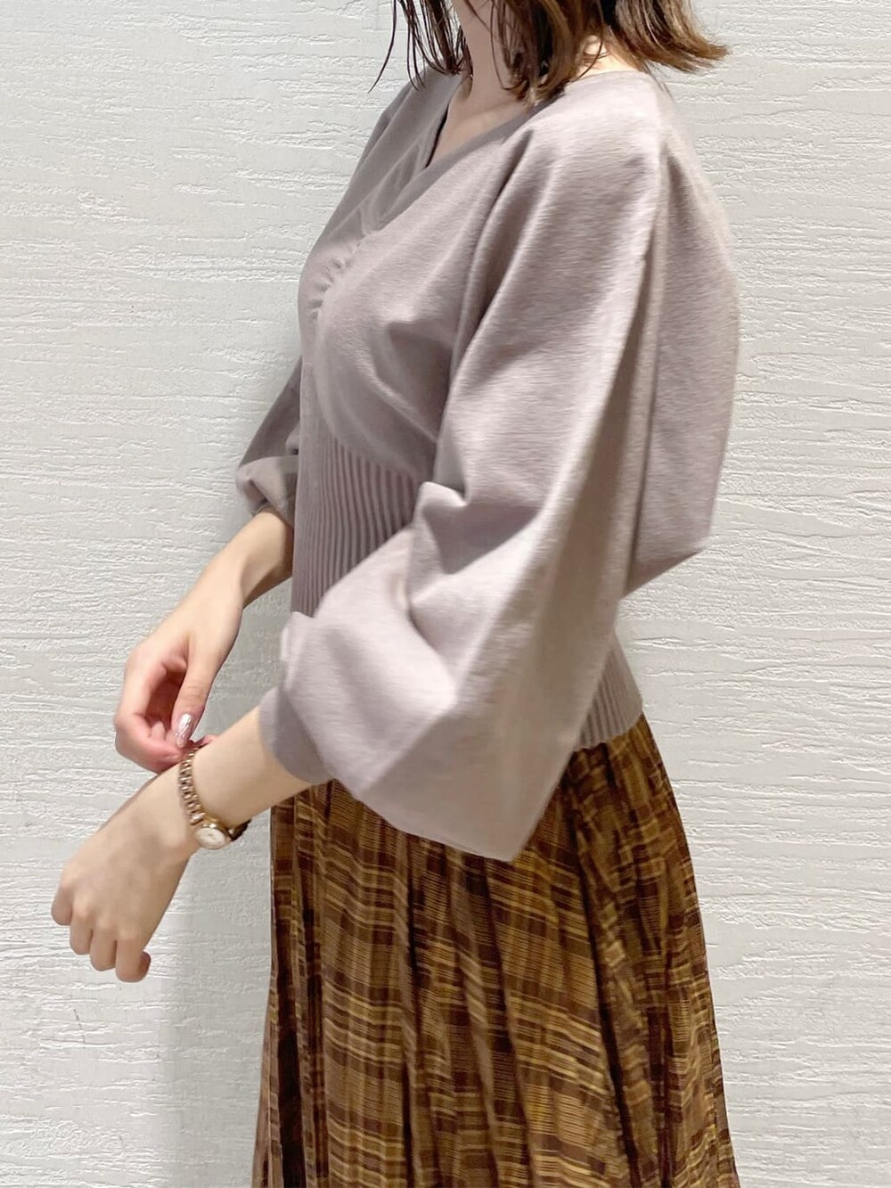 ブラウン系のスカート、ベージュ系のTシャツ/カットソー、ブラック系のブーツを着用したレディースの秋コーディネートの5枚目の写真
