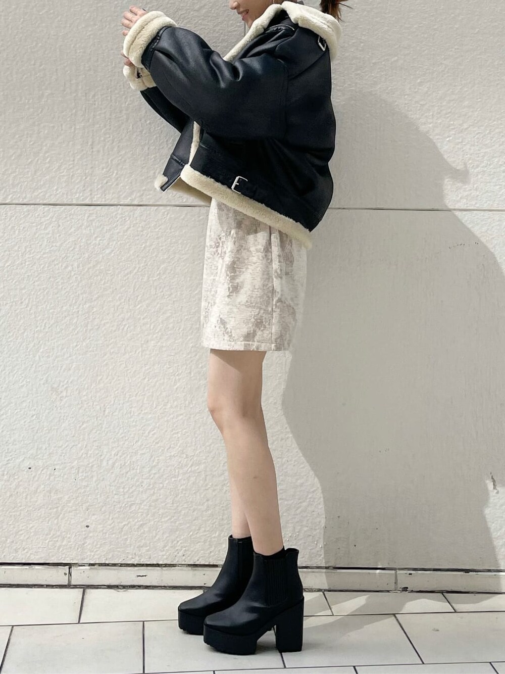 ブラック系のブルゾン、ベージュ系のスカート、ブラック系のブーツを着用したレディースの秋コーディネートの3枚目の写真