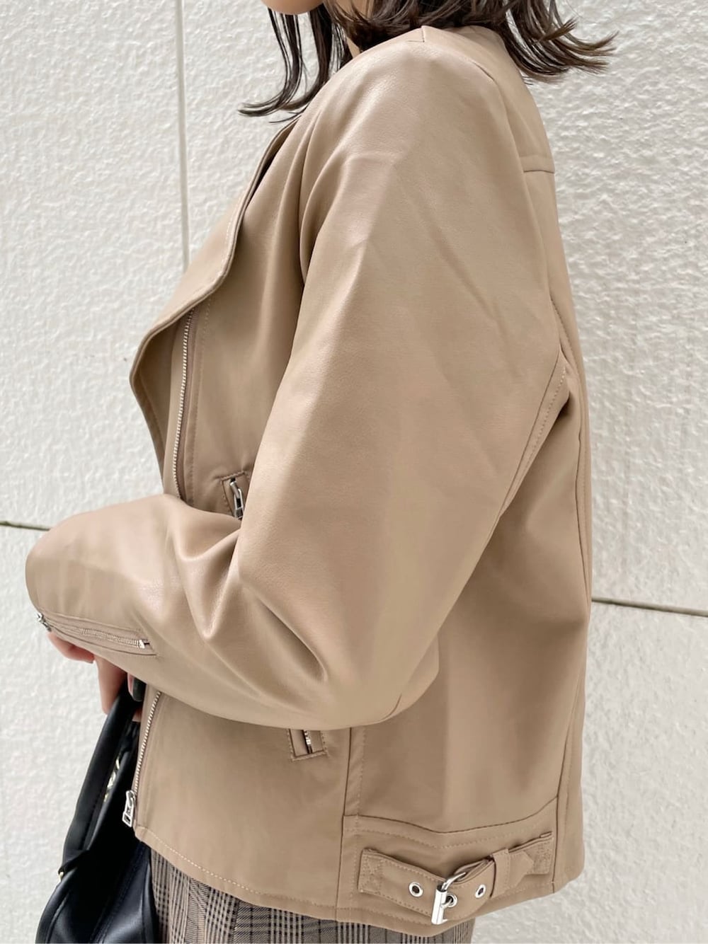 ベージュ系のライダースジャケット、ブラック系のブーツ、その他のジャンパースカートを着用したレディースの秋コーディネートの6枚目の写真