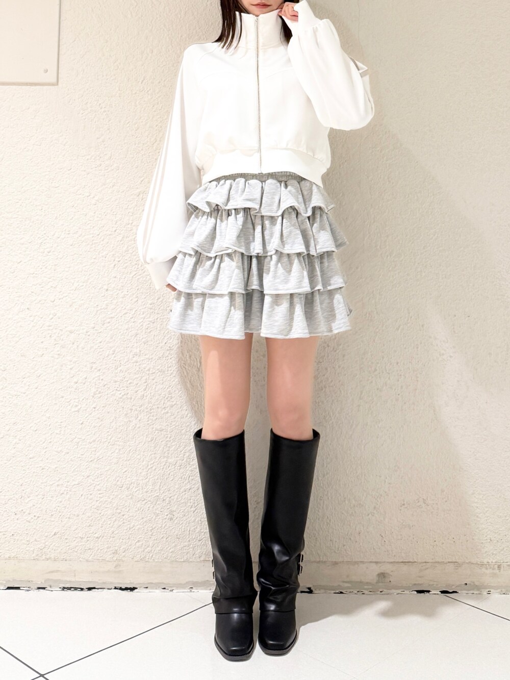 ブラック系のブーツ、グレー系のスカート、ホワイト系のその他アウターを着用したレディースの春コーディネートの2枚目の写真