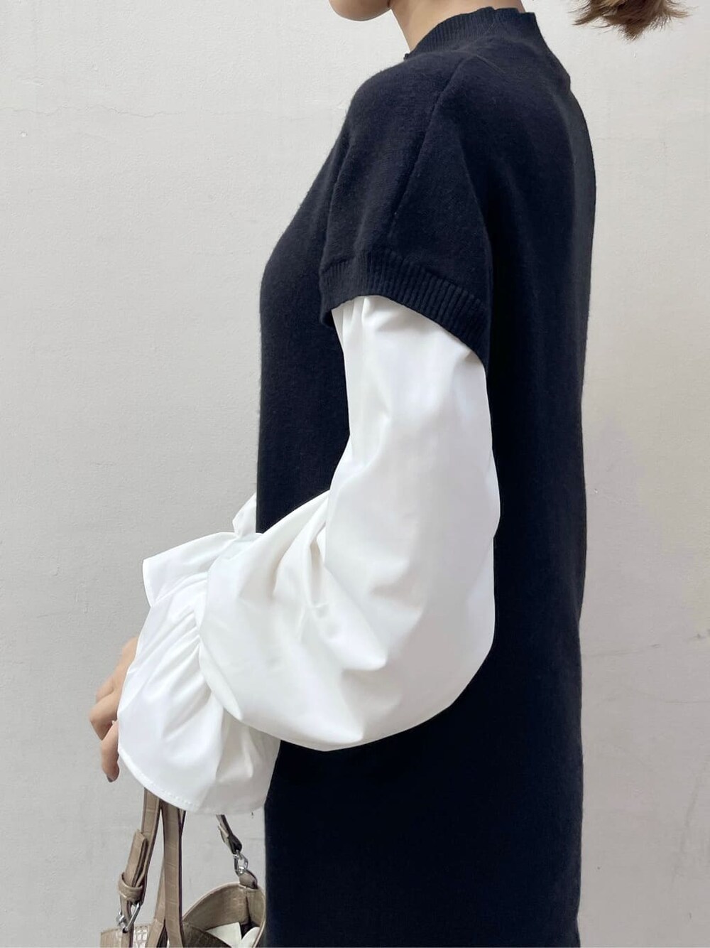 ブラック系のブーツ、ブラック系のワンピース、ベージュ系のハンドバッグを着用したレディースの秋コーディネートの6枚目の写真