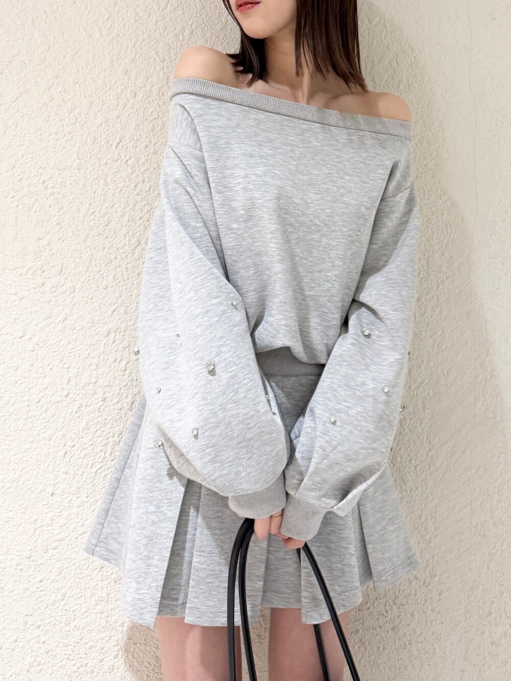 グレー系のスウェット、グレー系のスカート、ブラック系のハンドバッグを着用したレディースの春コーディネートの4枚目の写真