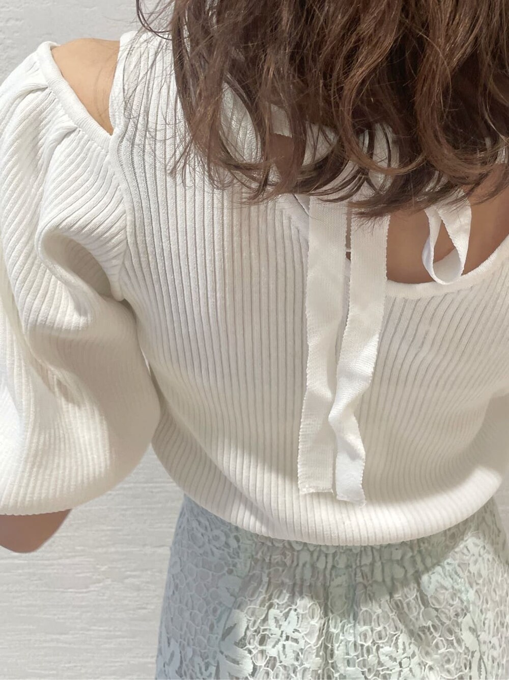 ホワイト系のニット/セーター、ブルー系のスカート、ブルー系のハンドバッグを着用したレディースの春コーディネートの7枚目の写真