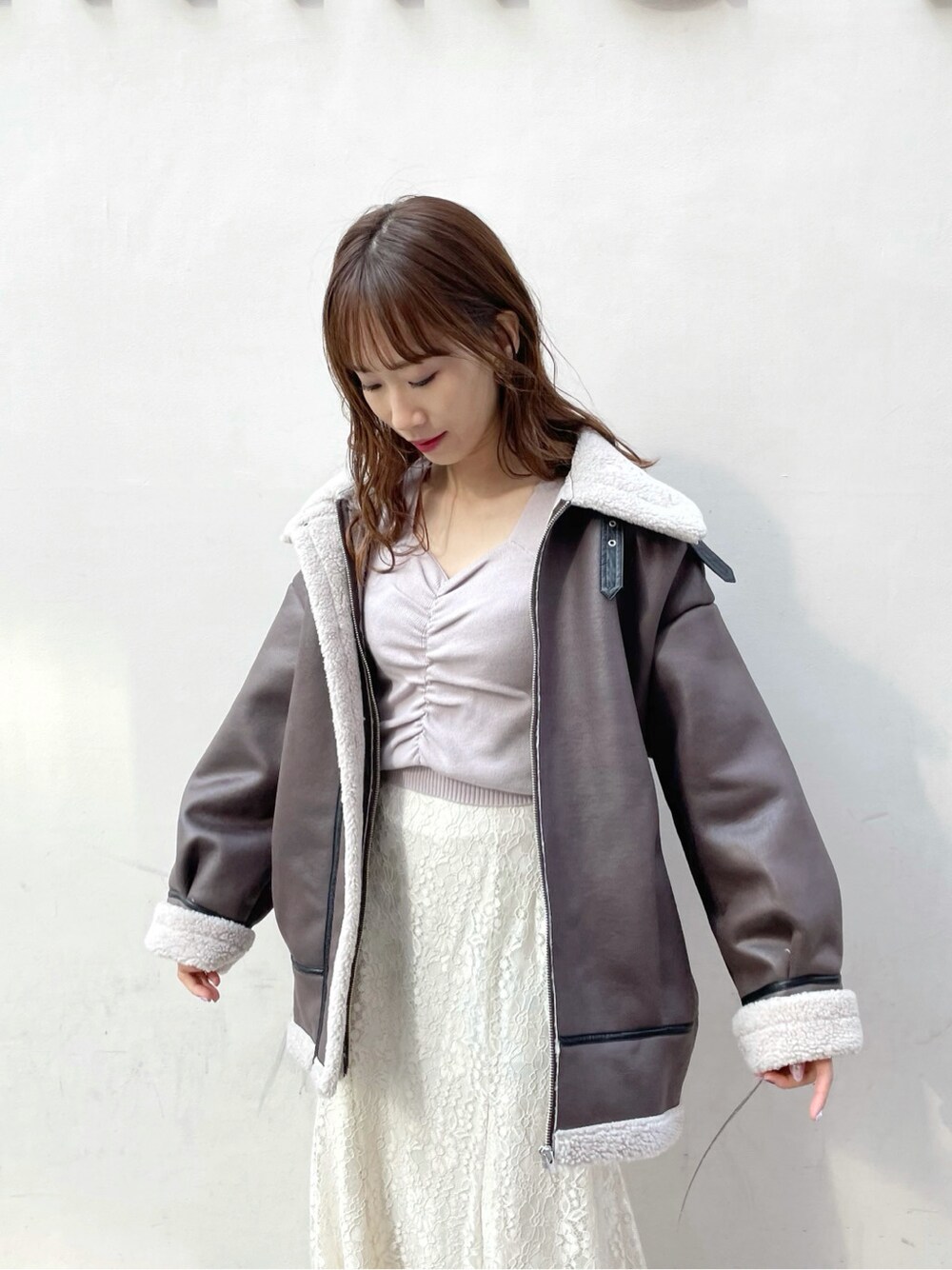 パープル系のニット/セーター、ホワイト系のブーツ、ホワイト系のスカートを着用したレディースの冬コーディネートの3枚目の写真