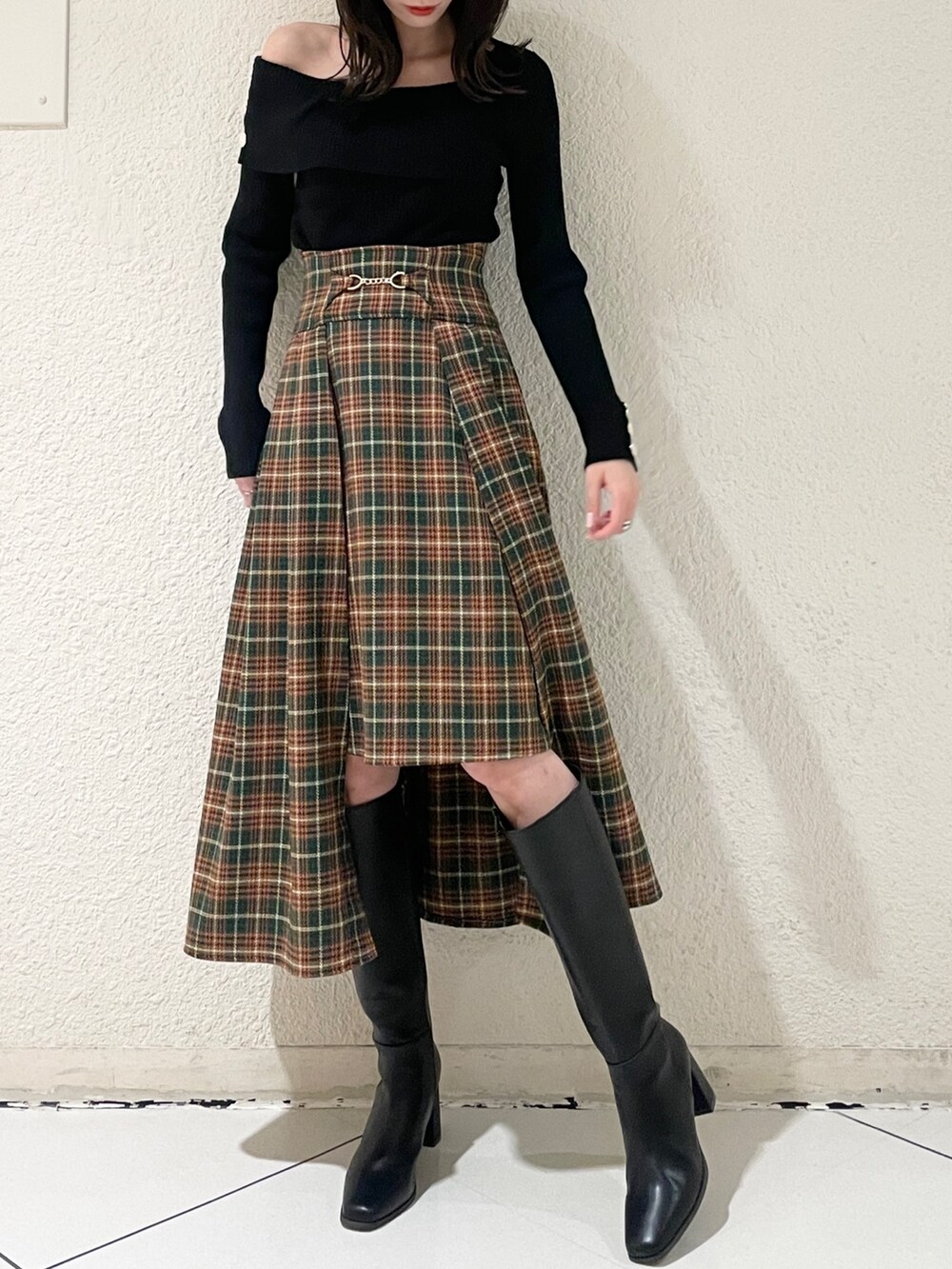 ブラック系のニット/セーター、ブラック系のブーツ、グリーン系のスカートを着用したレディースの秋コーディネートの3枚目の写真