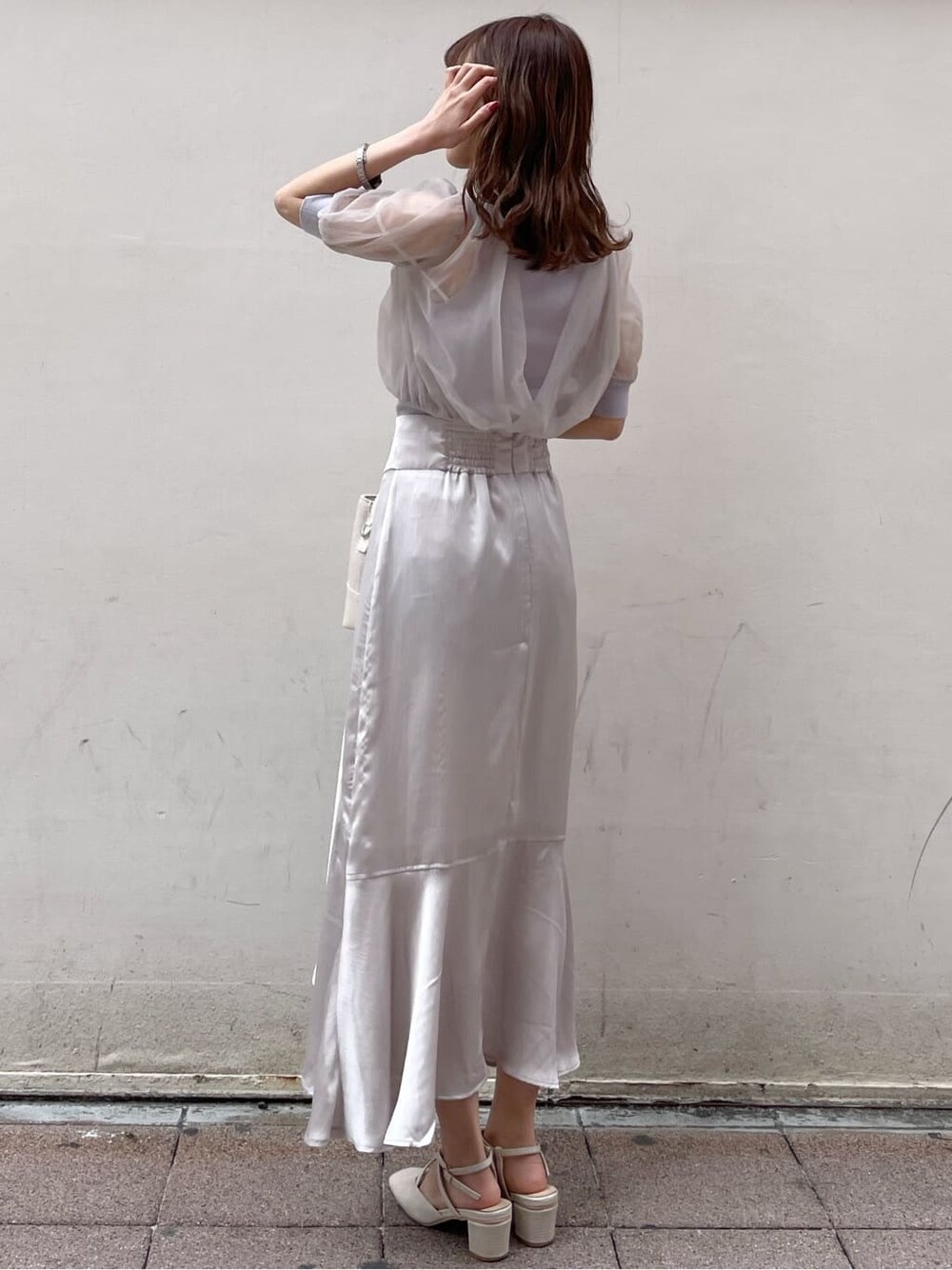 パープル系のニット/セーター、グレー系のスカート、ホワイト系のパンプスを着用したレディースの春コーディネートの3枚目の写真