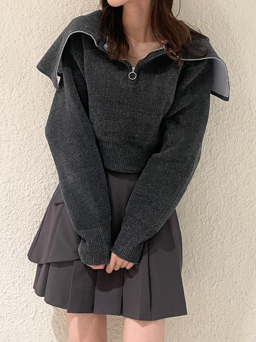 グレー系のニット/セーター、グレー系のスカート、ブラック系のブーツを着用したレディースの秋コーディネートの6枚目の写真