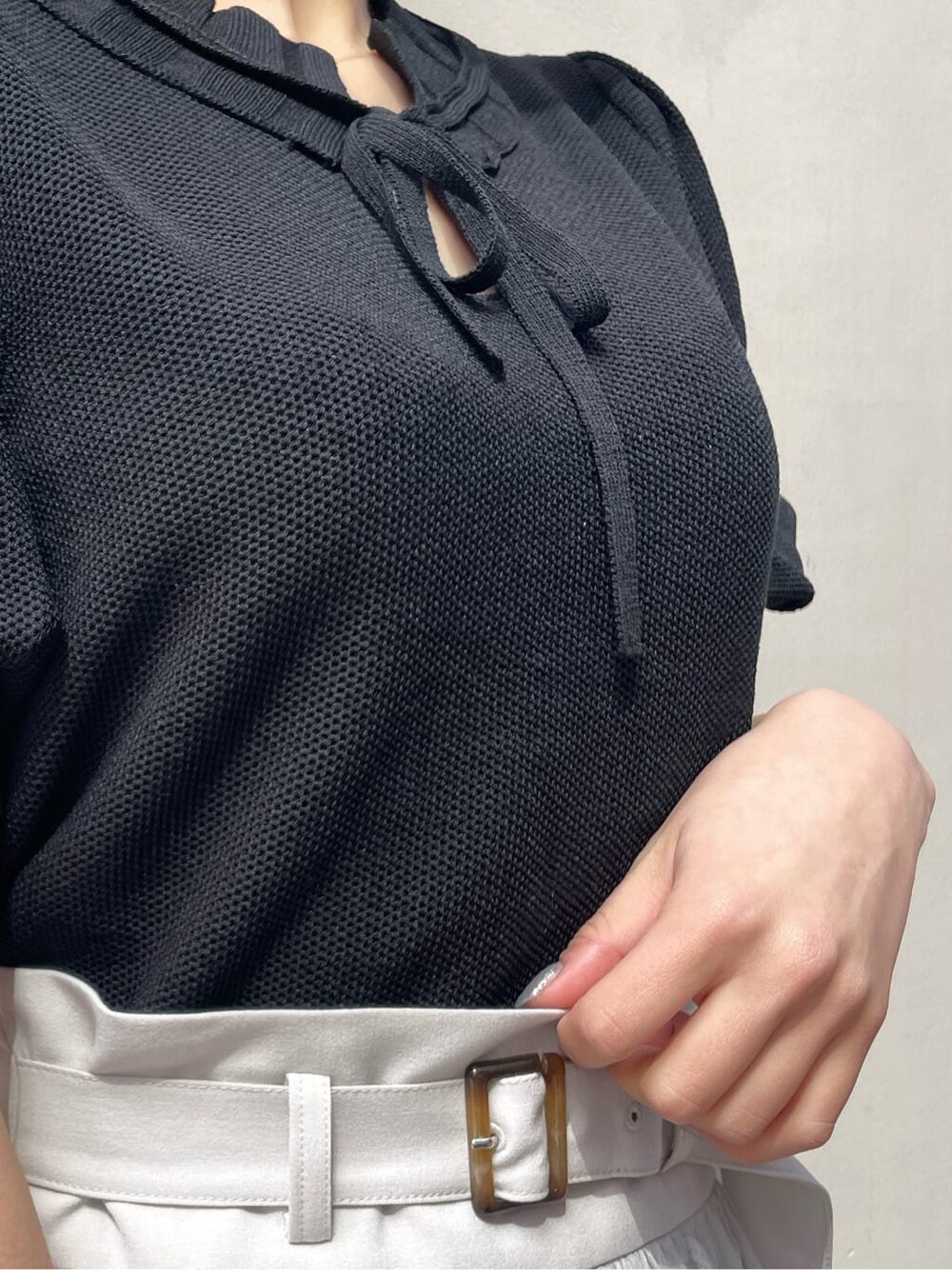 グレー系のスカート、ブラック系のサンダル、ホワイト系のニット/セーターを着用したレディースの春コーディネートの7枚目の写真