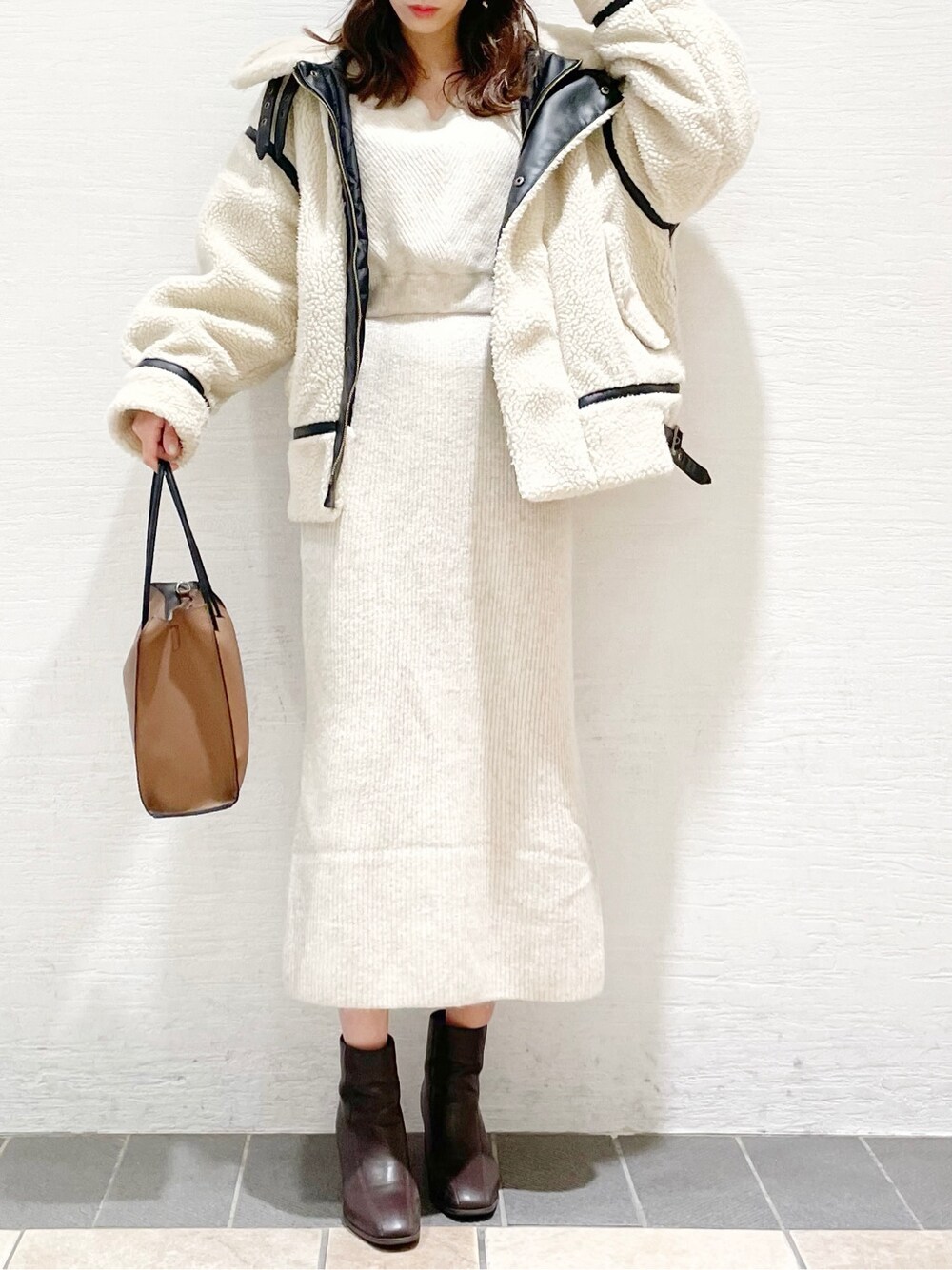 ベージュ系のワンピース、ブラウン系のブーツ、ブラウン系のハンドバッグを着用したレディースの冬コーディネートの4枚目の写真