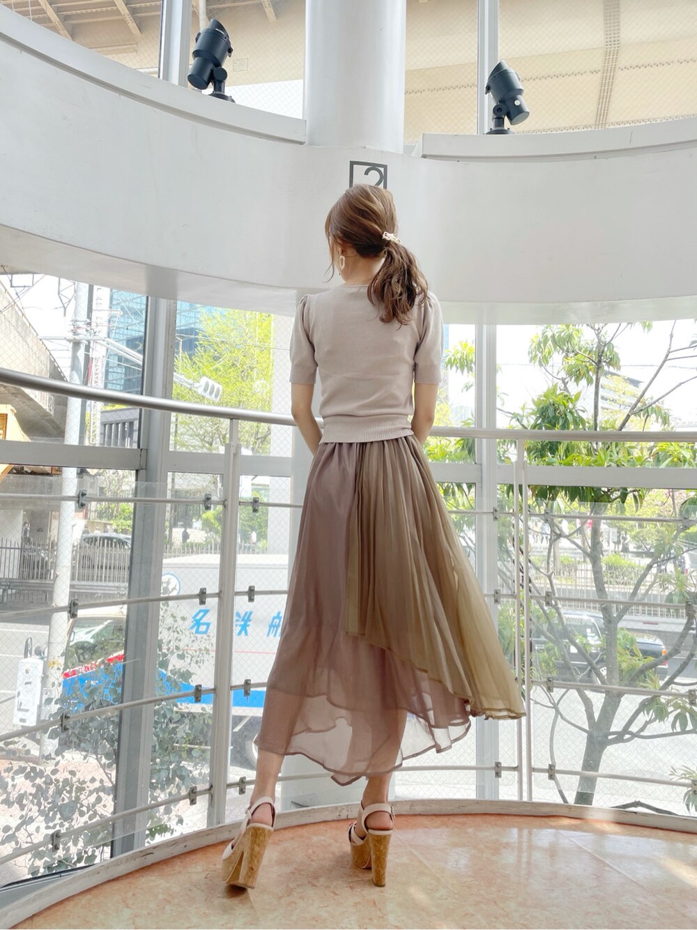 ブラウン系のスカート、ベージュ系のサンダル、ホワイト系のハンドバッグを着用したレディースの春コーディネートの3枚目の写真