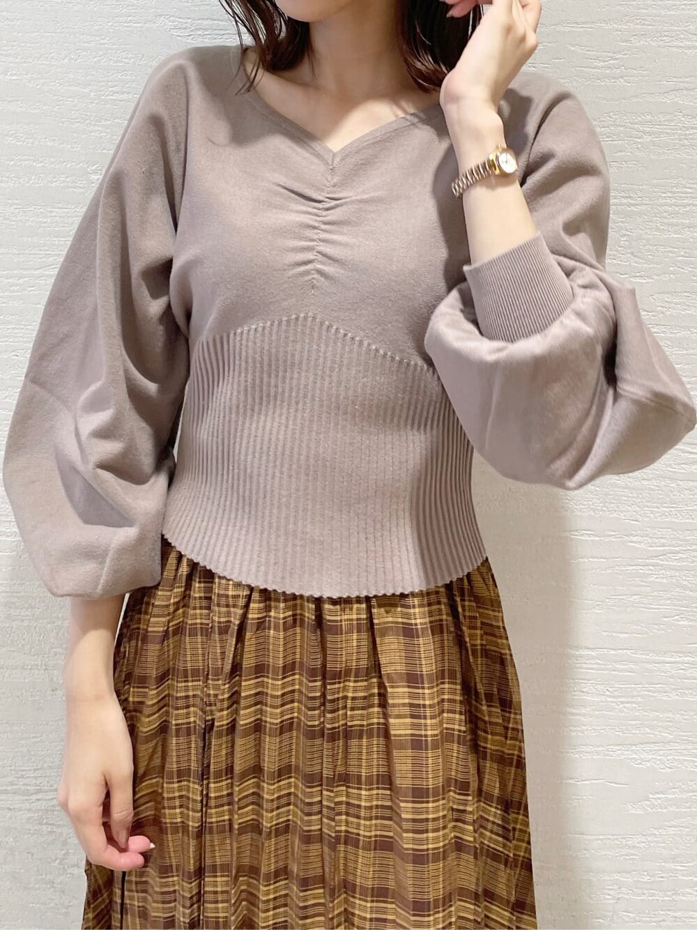 ブラウン系のスカート、ベージュ系のTシャツ/カットソー、ブラック系のブーツを着用したレディースの秋コーディネートの4枚目の写真