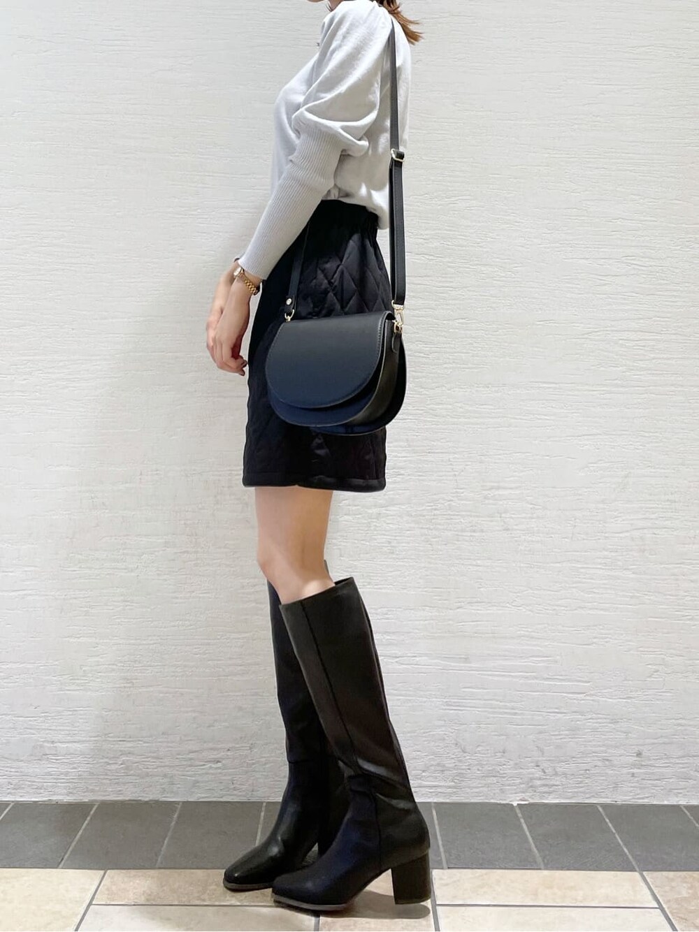 ブラック系のスカート、ブラック系のショルダーバッグ、グレー系のニット/セーターを着用したレディースの秋コーディネートの3枚目の写真