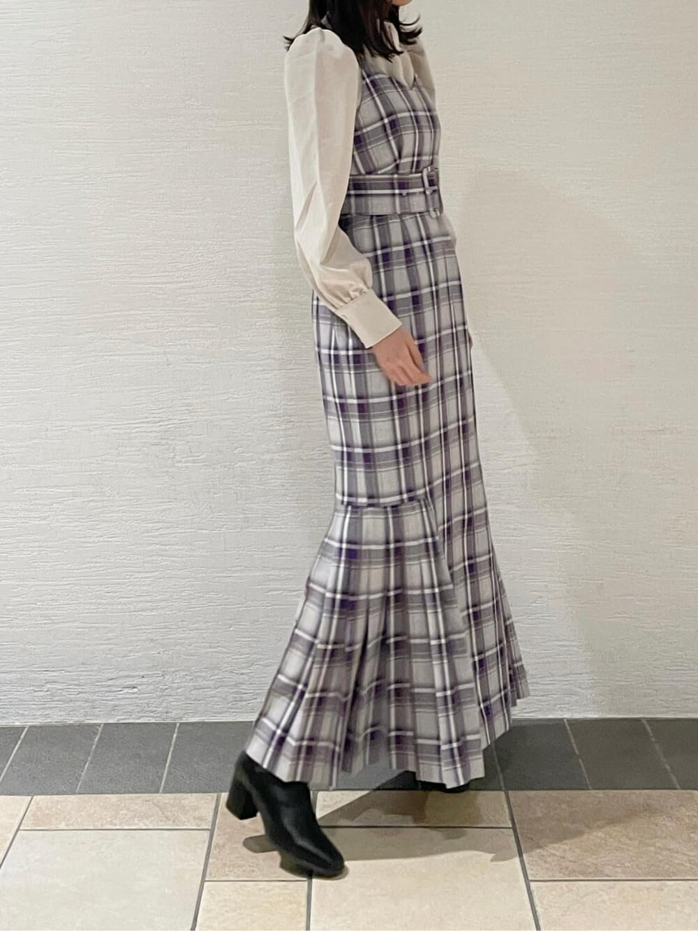 ブラック系のブーツ、ホワイト系のチェスターコート、パープル系のジャンパースカートを着用したレディースの冬コーディネートの4枚目の写真