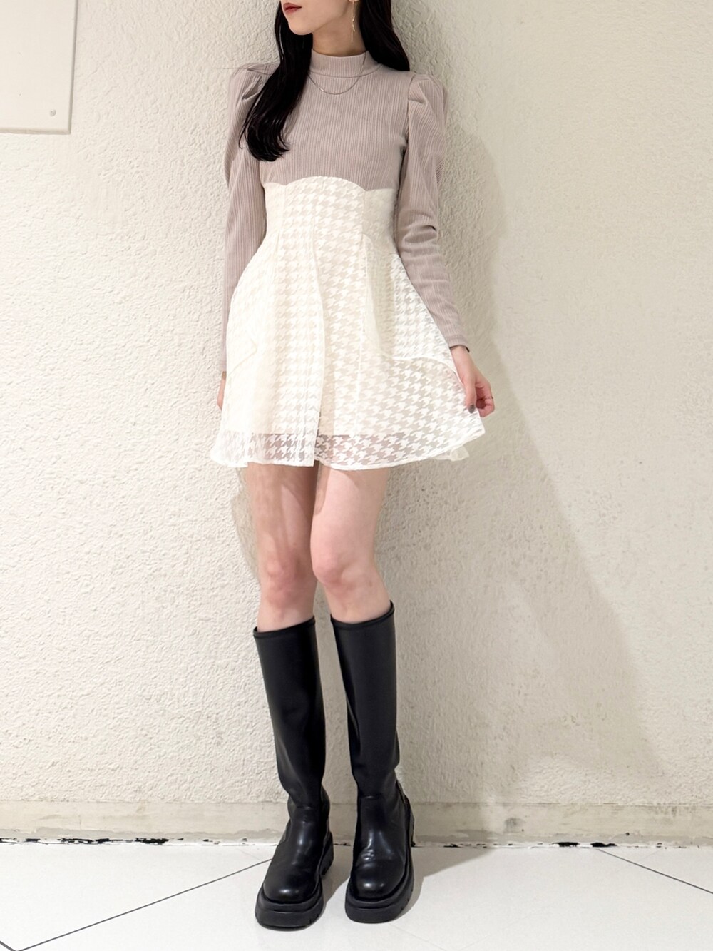 ベージュ系のワンピース、ブラック系のブーツを着用したレディースの春コーディネートの2枚目の写真