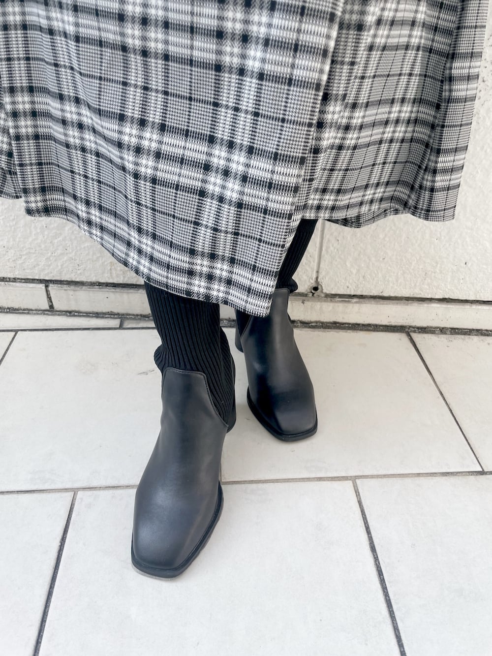 ブラック系のニット/セーター、グレー系のスカート、ブラック系のブーツを着用したレディースの秋コーディネートの8枚目の写真