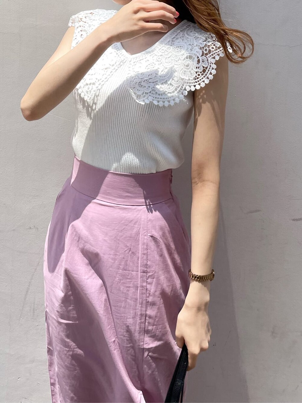 ブラック系のハンドバッグ、ピンク系のスカート、パープル系のサンダルを着用したレディースの夏コーディネートの5枚目の写真