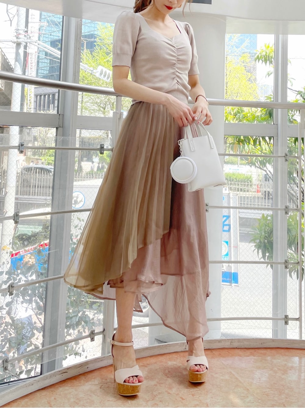 ブラウン系のスカート、ベージュ系のサンダル、ホワイト系のハンドバッグを着用したレディースの春コーディネートの4枚目の写真